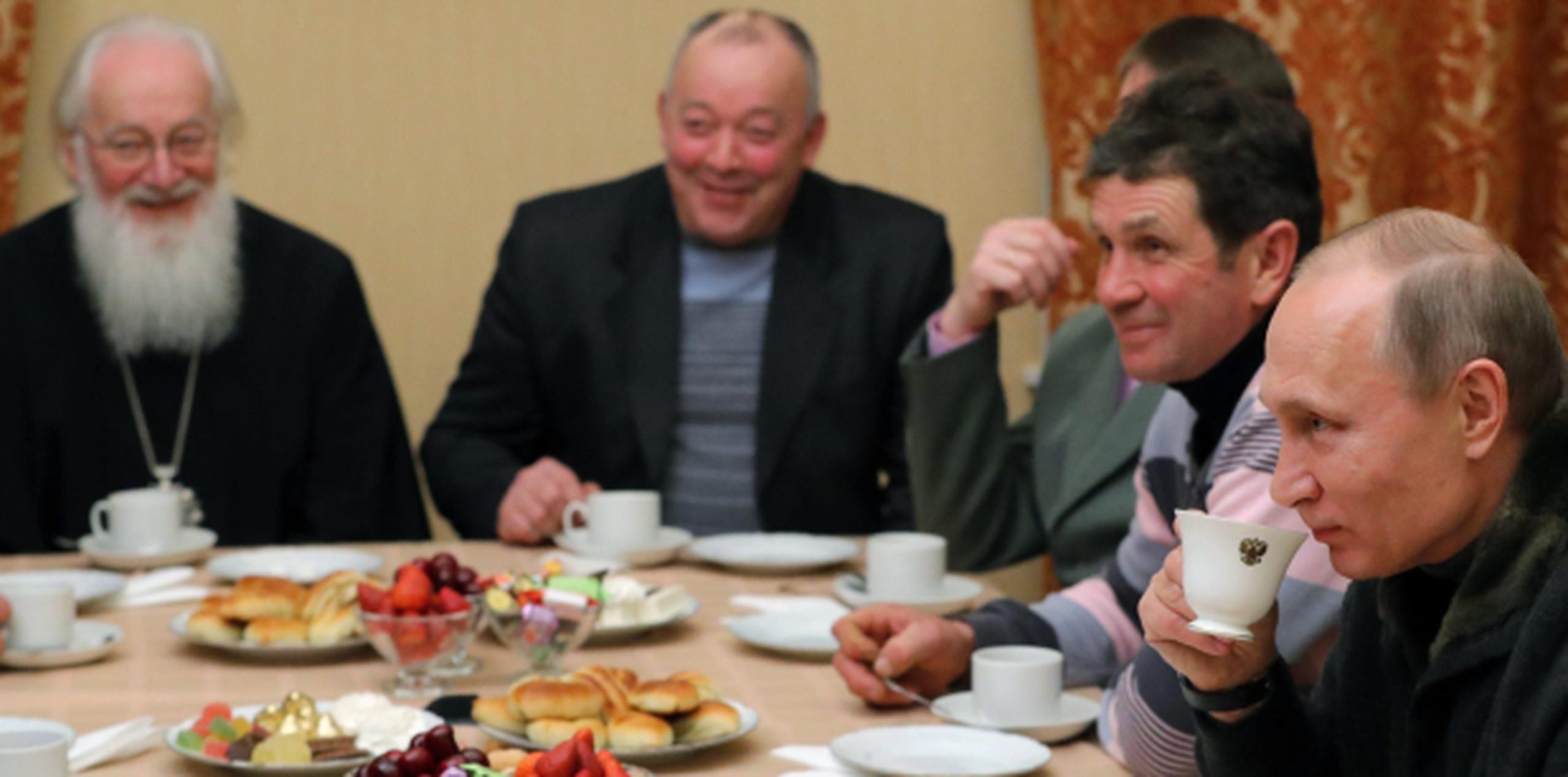 Estados Unidos ha asegurado que el gobierno que dirige Vladimir Putin, aquí tomando de una taza en una cena navideña con pescadores, interfirió en las elecciones presidenciales. (EFE)