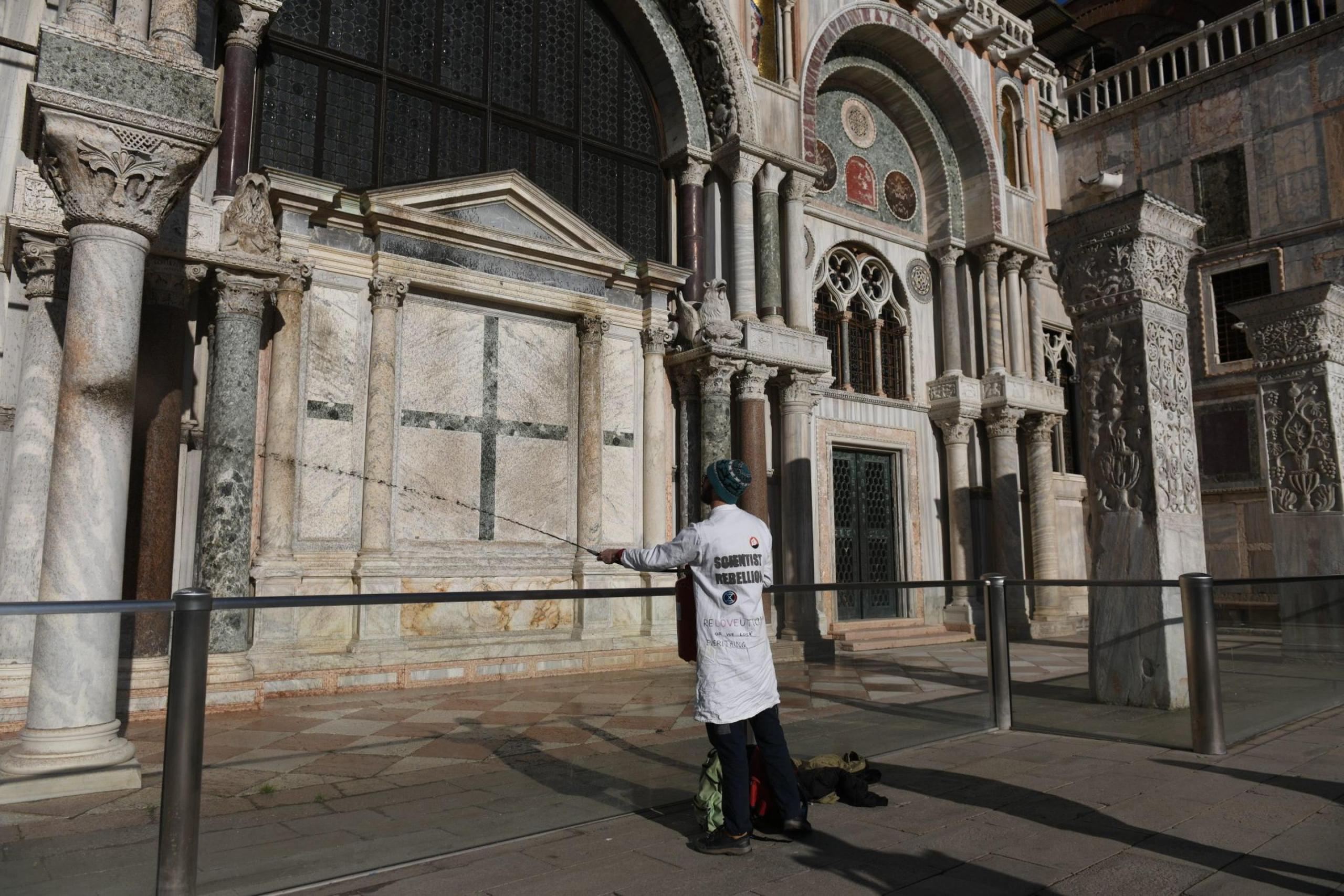 Un activista climático rocía barro en el exterior de la Basílica de San Marcos durante una protesta en Venecia, Italia, el 7 de diciembre de 2023. Los manifestantes utilizaron extintores para rociar barro líquido en las paredes de la iglesia, antes desplegando una pancarta que decía "fondo de reparación". (Protestas, Italia, Niza, Venecia) (EFE/EPA/EDOARDO FIORETTO)
