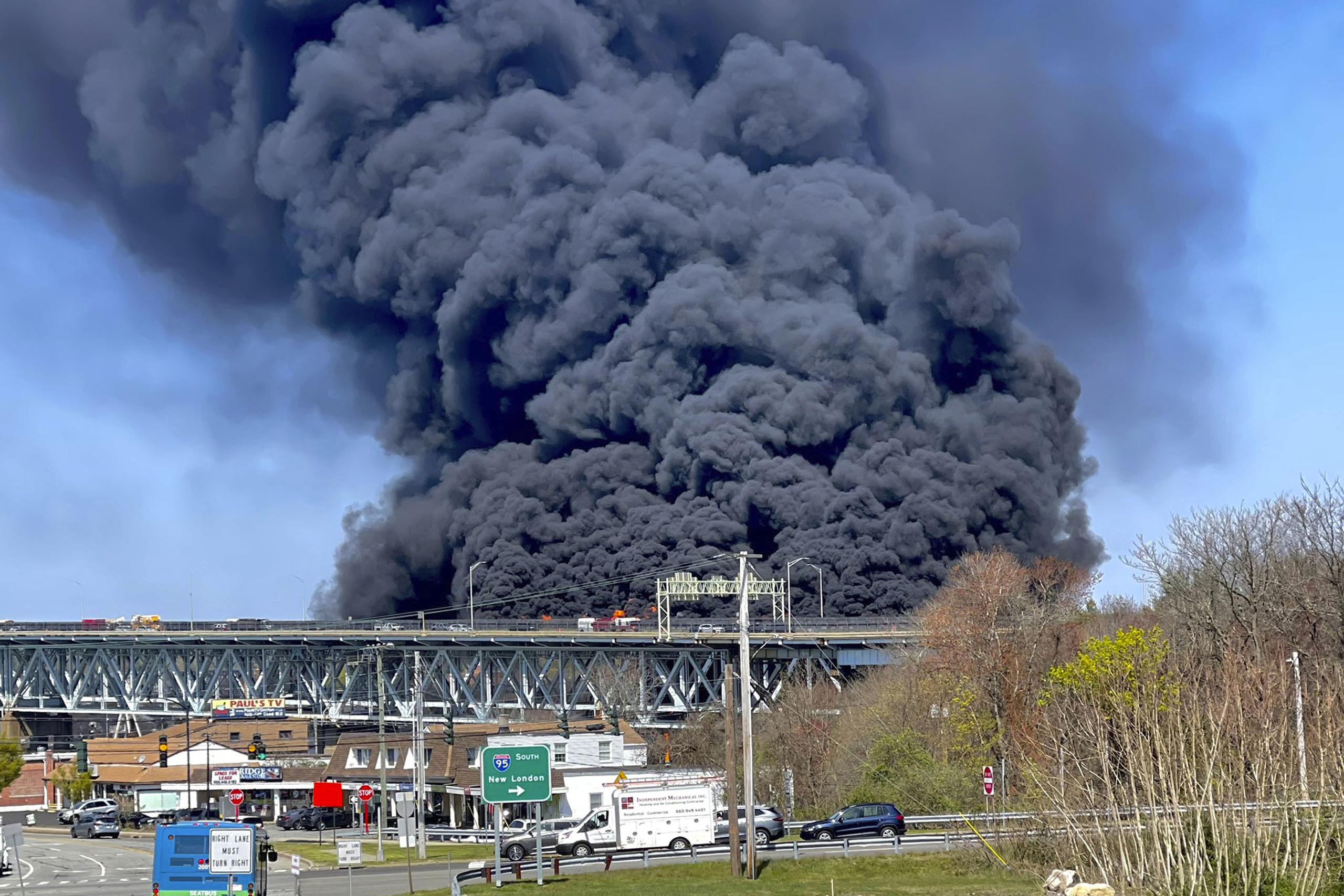Gruesas columnas de humo se alzan de un incendio provocado por el choque entre un camión cisterna de combustibles y un auto en el puente  Gold Star Memorial en Groton,  Connecticut.