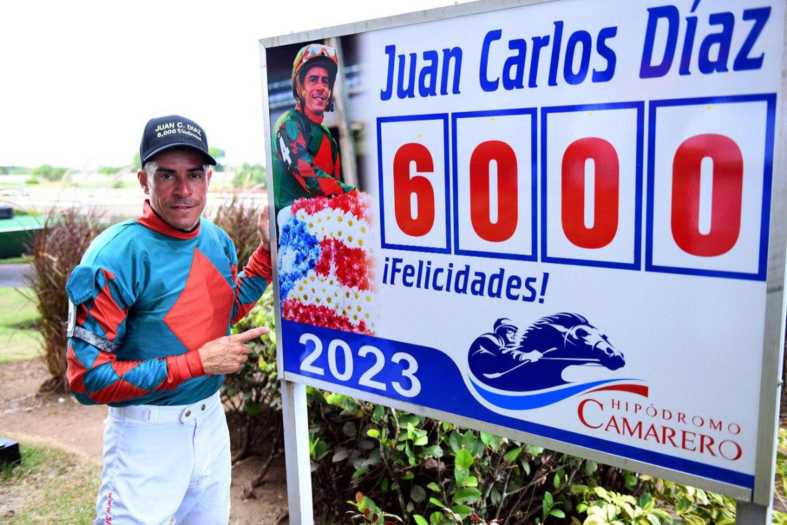 Juan Carlos Díaz posa junto a una pancarta que le certifica como ganador de 6,000 carreras.  (Camarero)