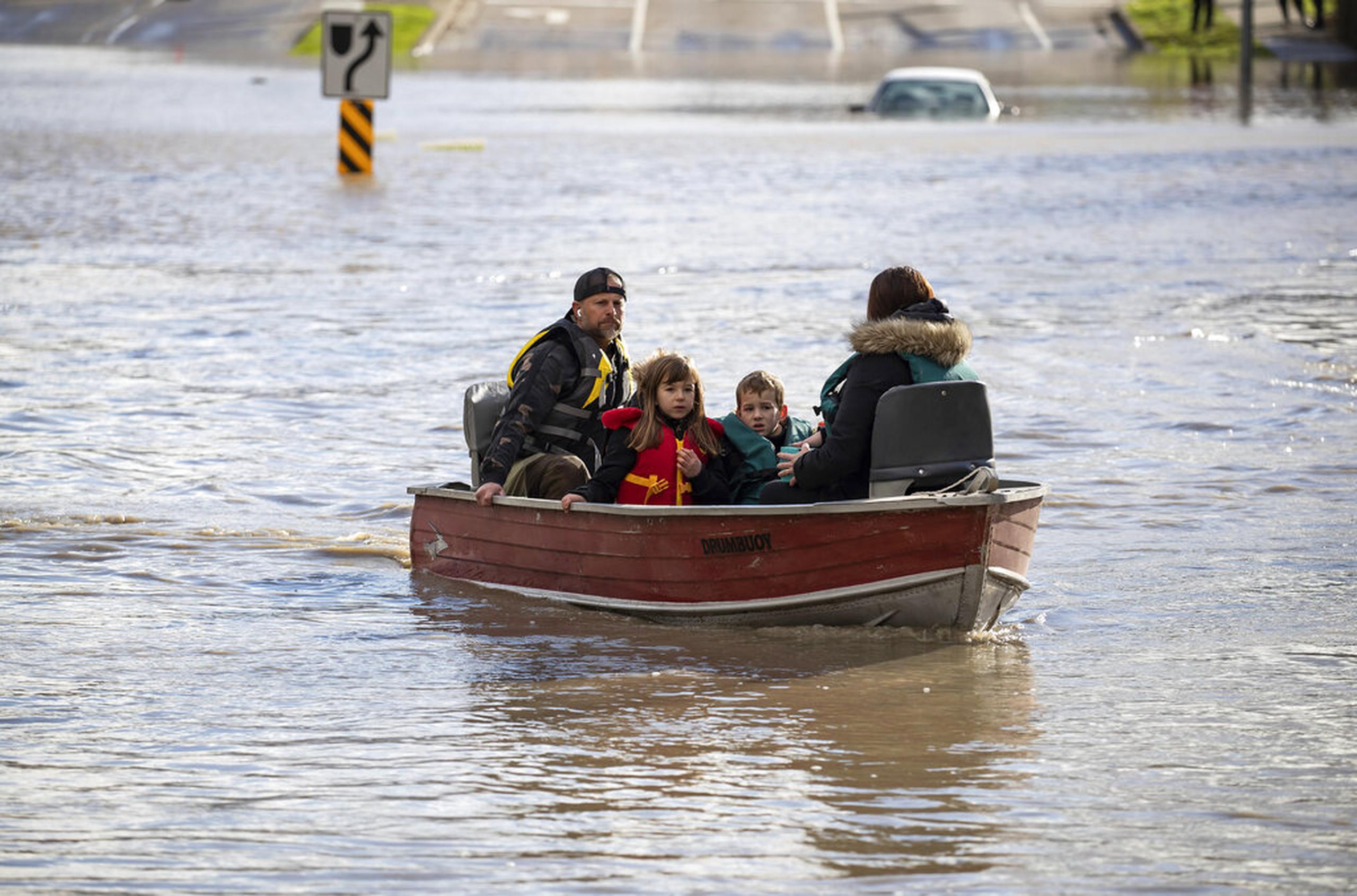 Una mujer y dos niños que estaban varados debido a las inundaciones son rescatados por un voluntario con un bote en Abbotsford, Columbia Británica, el 16 de noviembre de 2021.