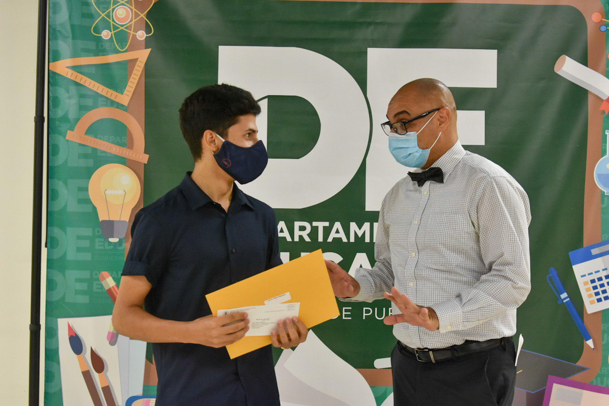Uno de los estudiantes recibe la beca por parte del secretario de Educación, Eligio Hernández Pérez.