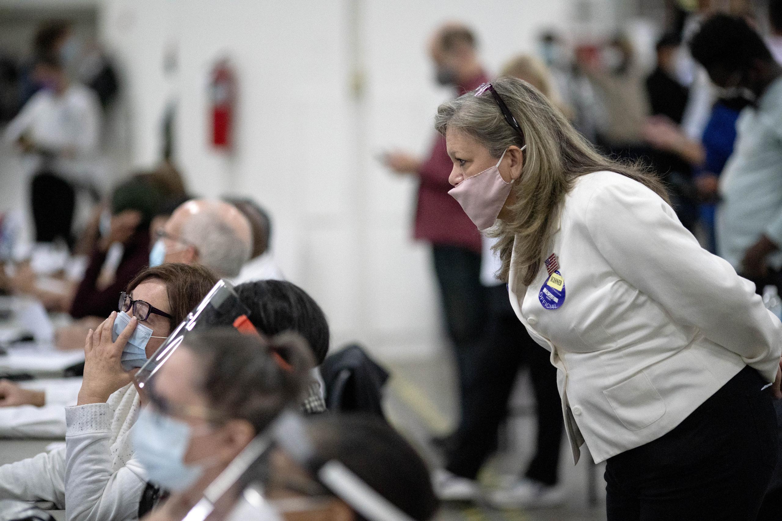 Una aspirante republicana a las elecciones (derecha) observa a los inspectores electorales mientras examinan una papeleta durante el conteo de votos en la junta central de recuento de Detroit.