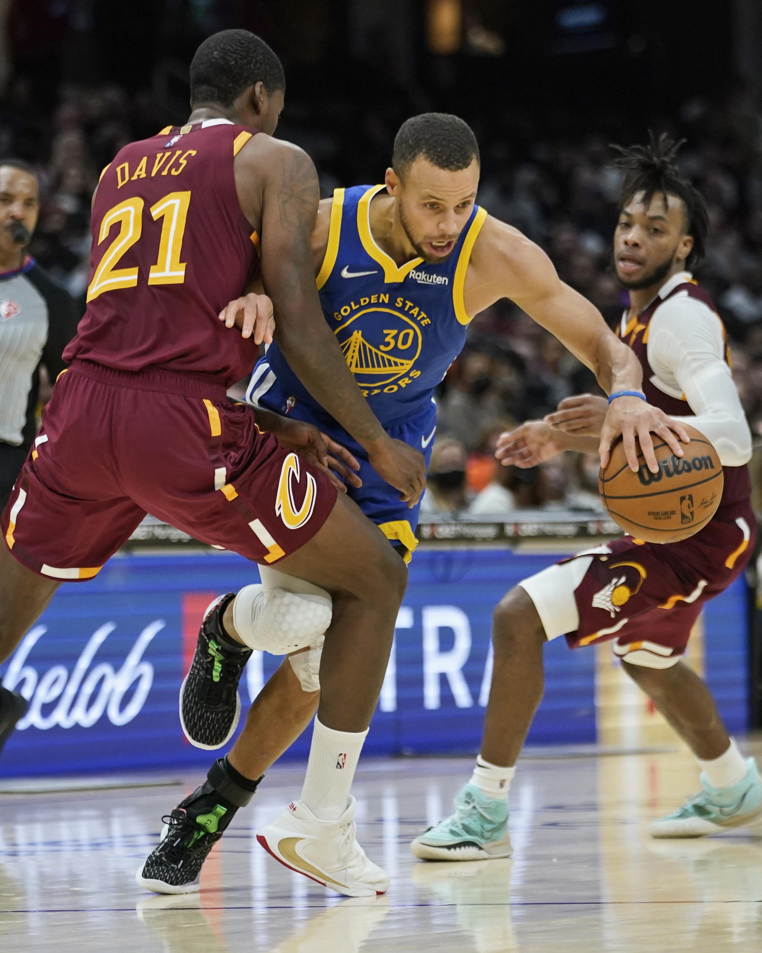 Ed Davis, de los Cavaliers de Cleveland, comete una falta al intentar detener a Stephen Curry, de los Warriors, durante el desafío del jueves en que Curry coló 20 puntos en el último cuarto para darle la ventaja y la victoria a su equipo.