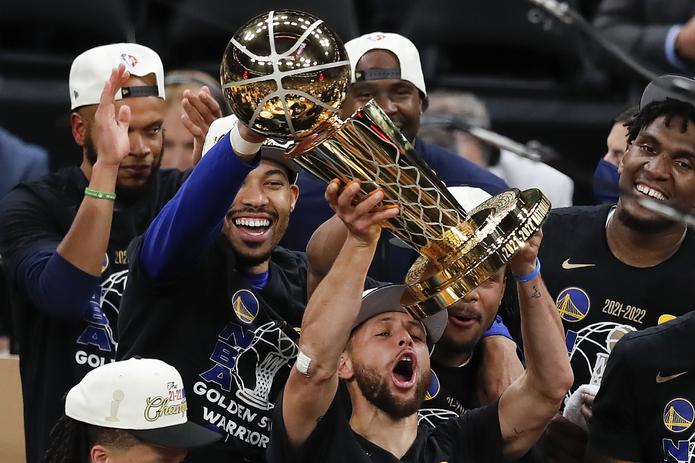 El armador Stephen Curry levanta el trofeo de campeón de la NBA en medio de sus compañeros de los Warriors de Golden State.