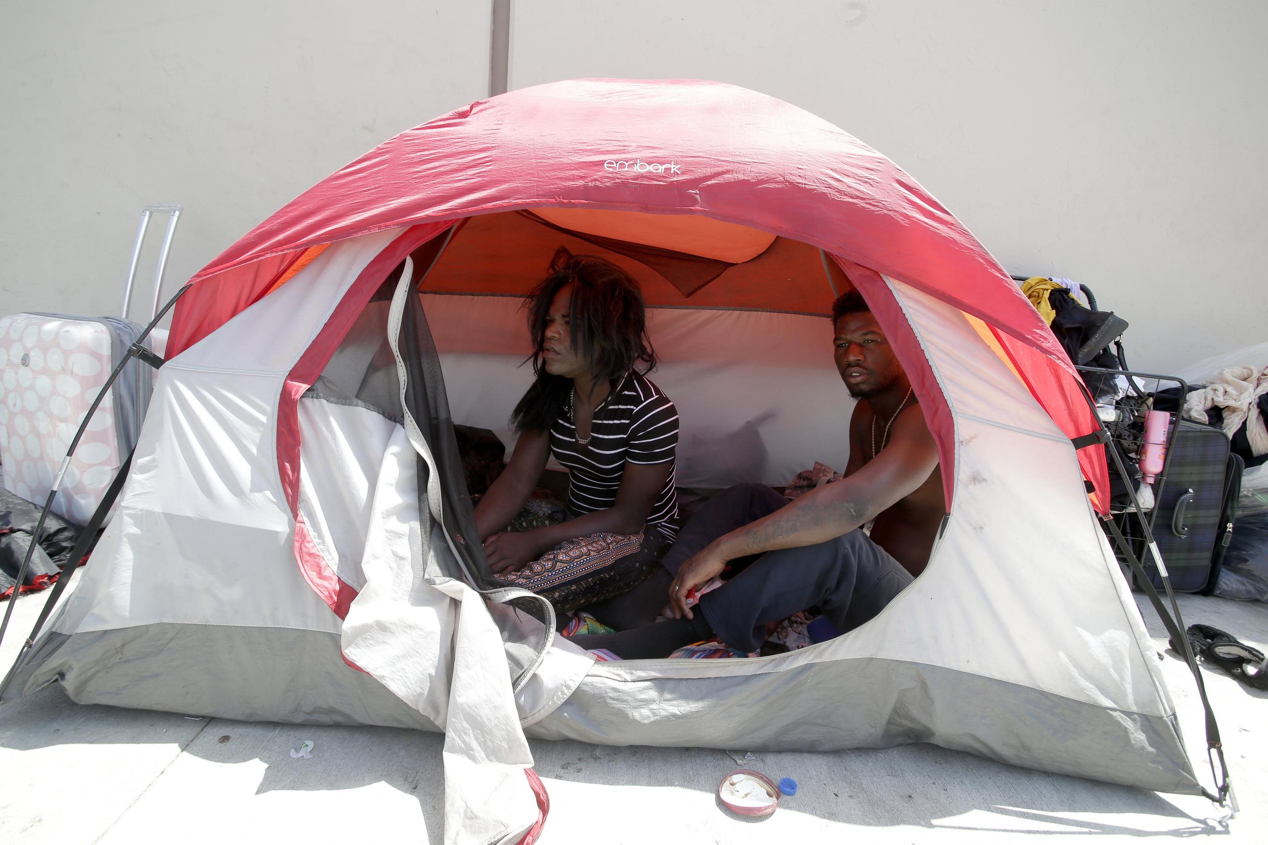 Una pareja sin hogar sentados en su tienda de campaña en un pequeño campamento de personas sin hogar, en una calle de Hollywood, California. (EFE / EPA / Mike Nelson)