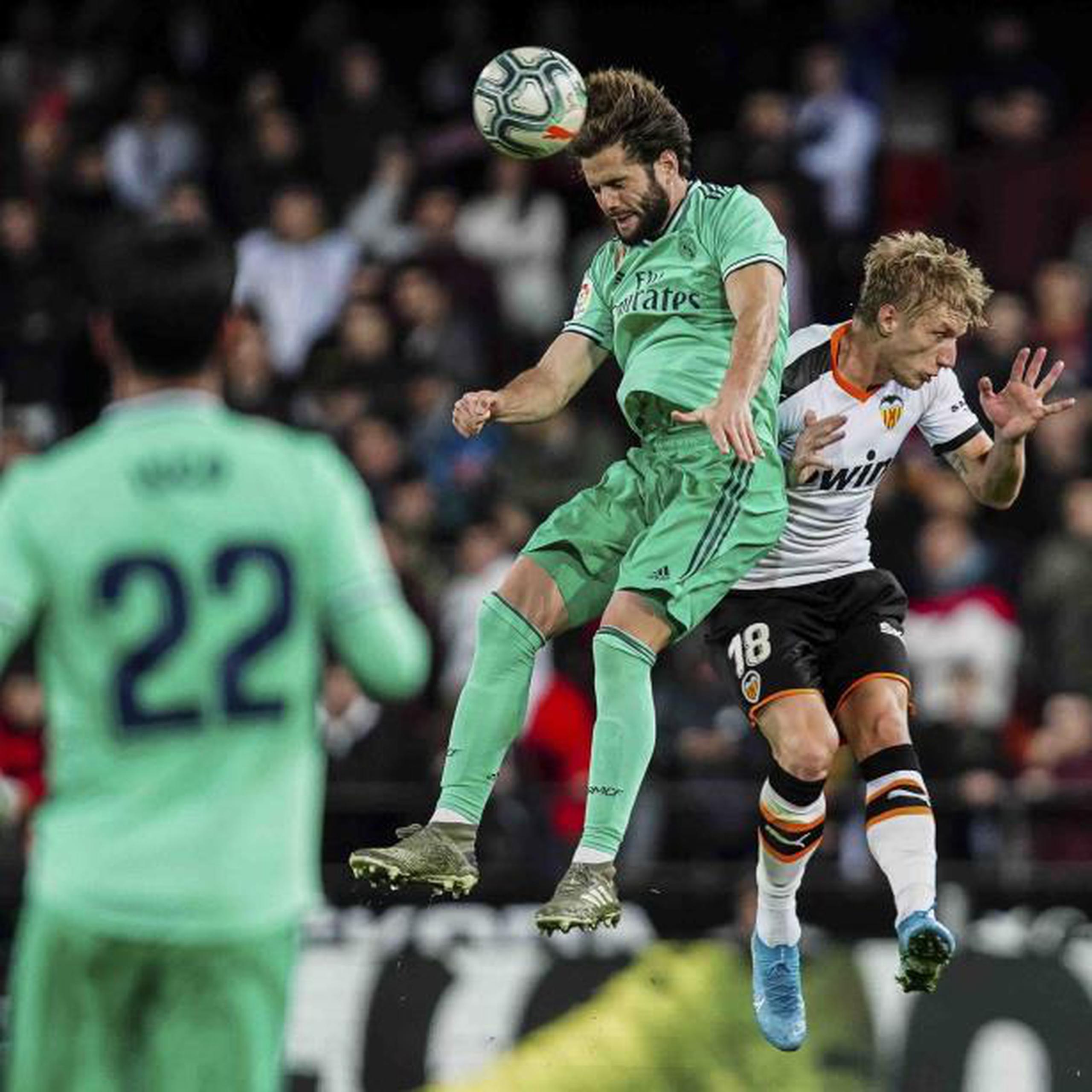 Nacho, del Real Madrid, cabecea el balón ante la cercanía de Daniel Wass de Valencia. (AP)