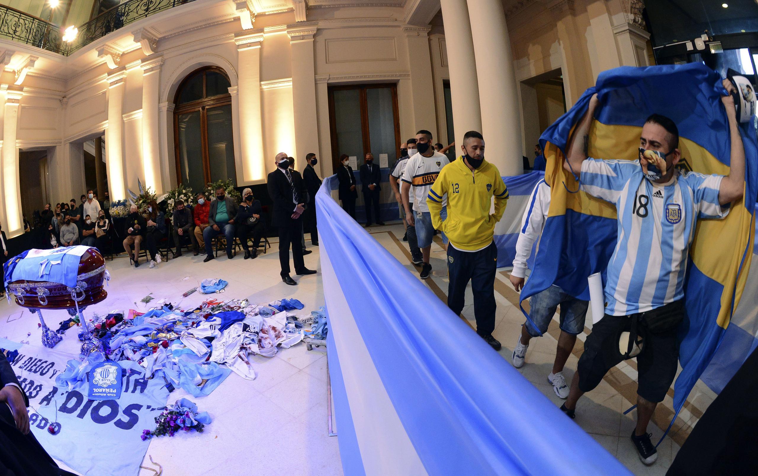 Los visitantes arrojaron flores y camisetas de fútbol por encima del largo parapeto que los separaba del ataúd cubierto por una bandera argentina.