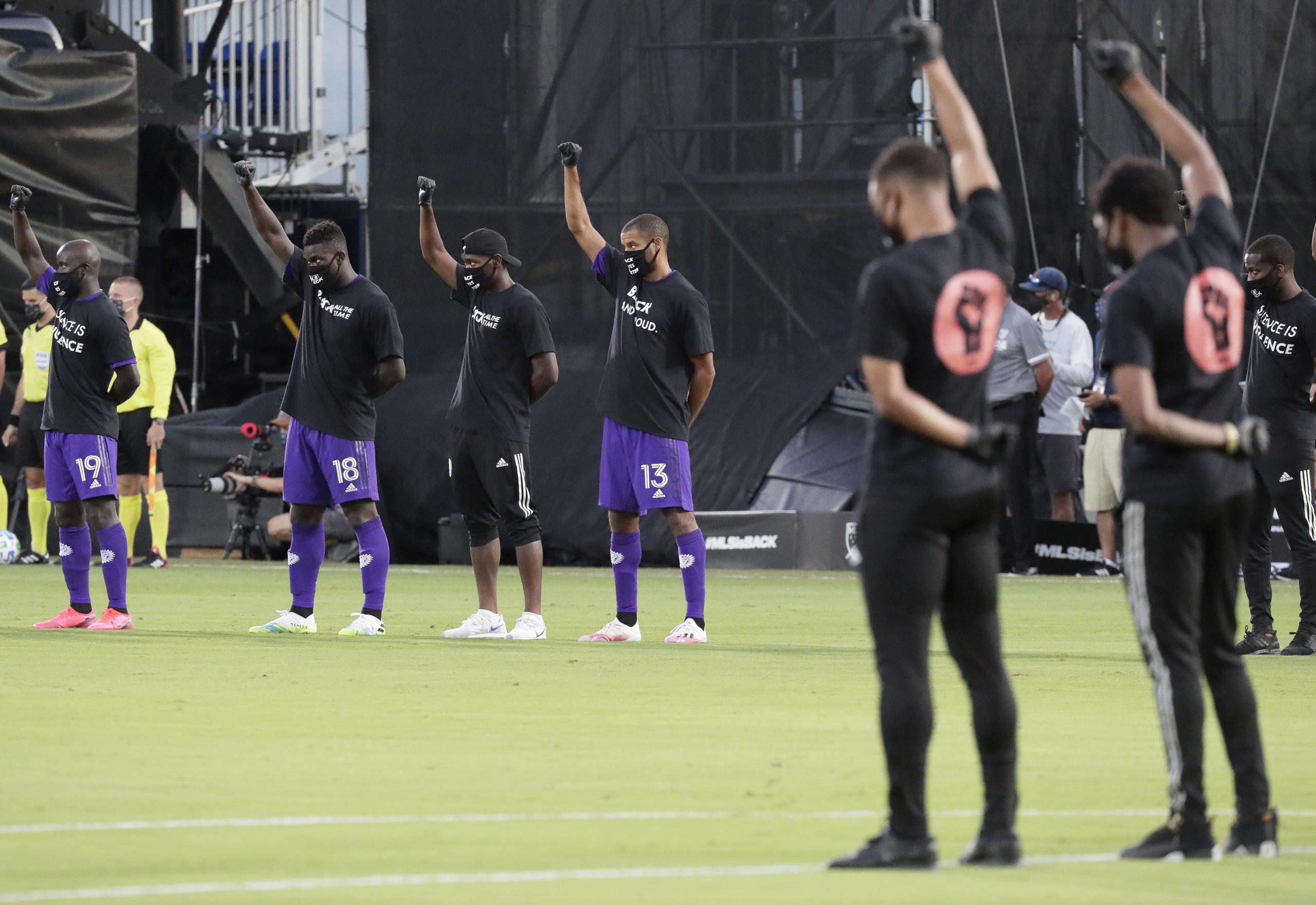 Jugadores del Orlando City (izquierda) levantan un puño como una protesta contra la injusticia social antes de poner en marcha un torneo que marca la reanudación de la actividad en la MLS, interrumpida por la pandemia de coronavirus.