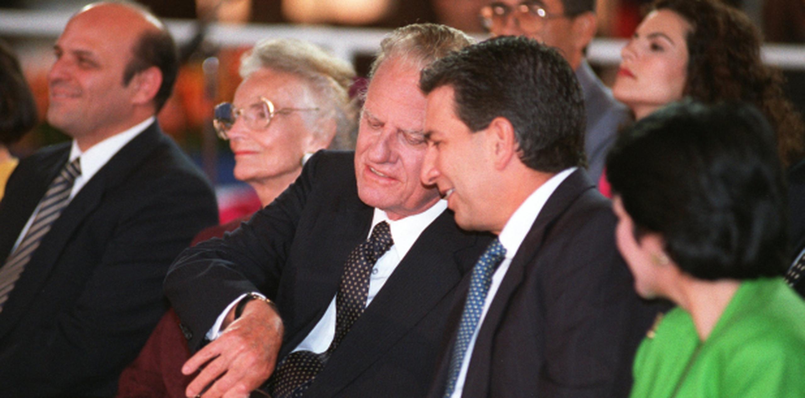 Graham le muestra su reloj al entonces gobernador Pedro Rosselló. Al fondo se ve al entonces alcalde de San Juan, Héctor Luis Acevedo. (Archivo)