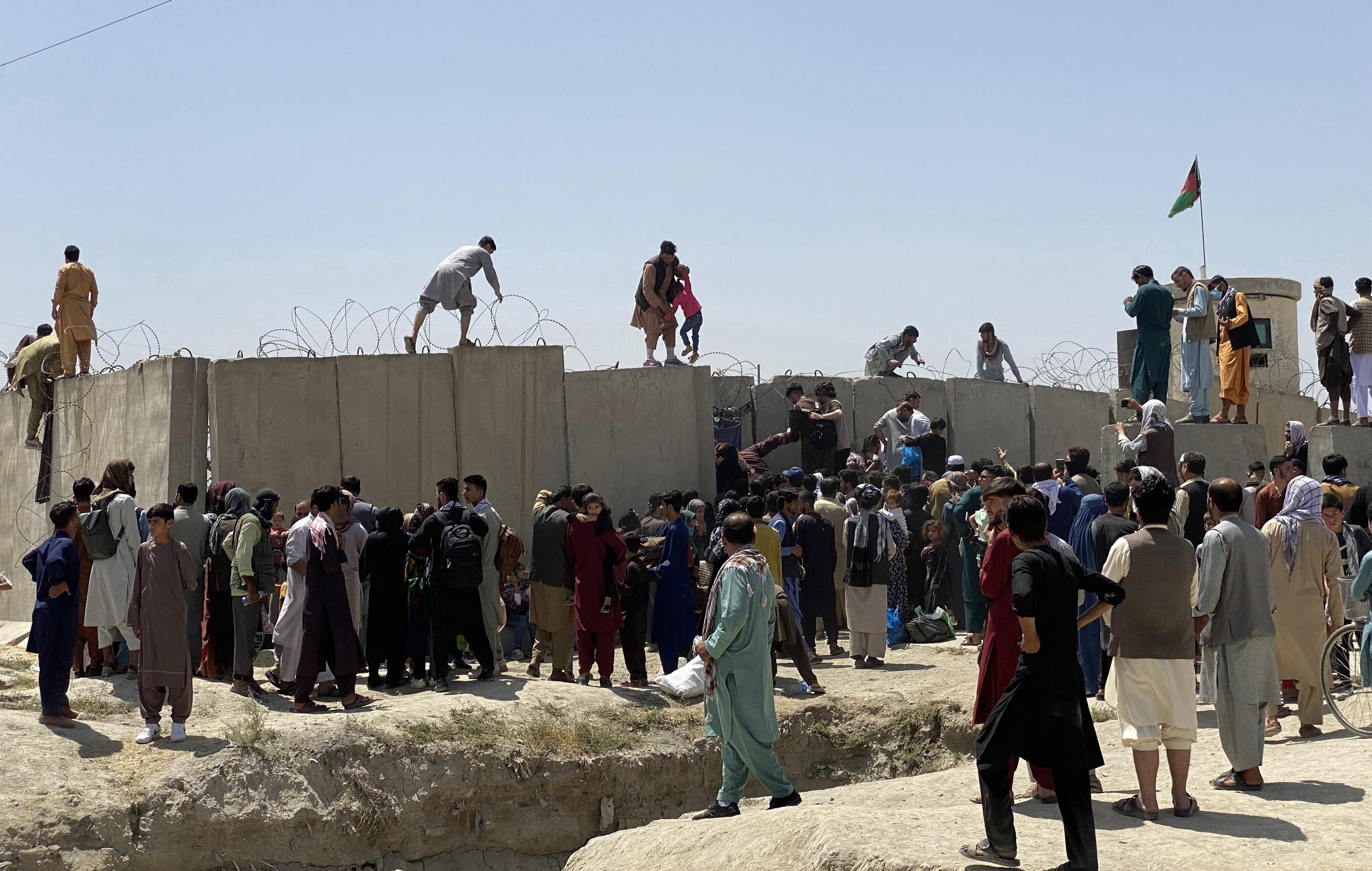 Afganos se agolpan a lo largo del muro del aeropuerto internacional Hamid Karzai antes de saltarlo en un intento de abandonar el país, este lunes en Kabul, después de darse a conocer de que el propio presidente afgano, Ashra Ghani, huyera ayer en secreto. EFE/STRINGER
