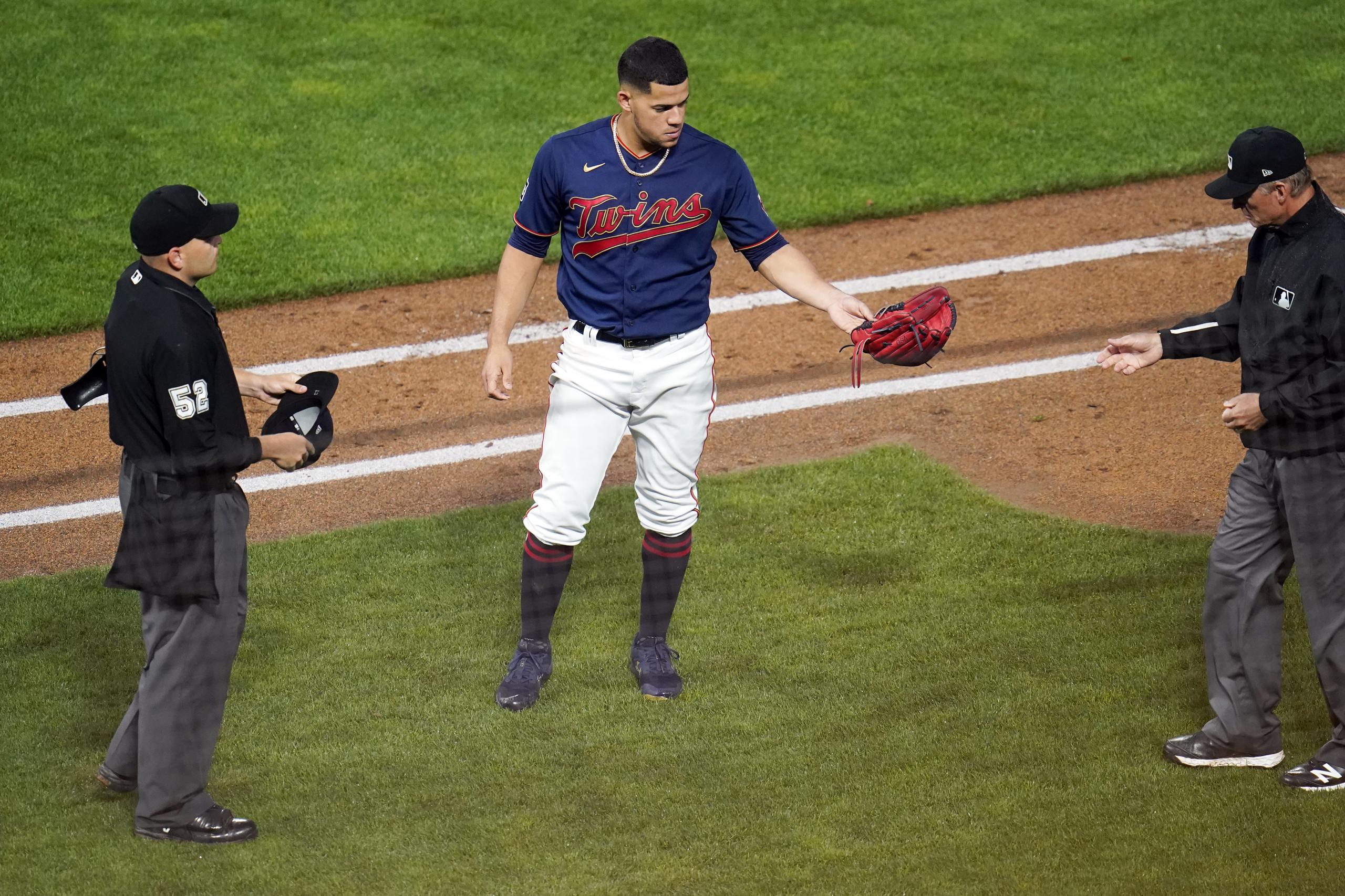 El puertorriqueño José Berríos, lanzador de los Twins de Minnesota, ofrece su guante para inspección de uno de los árbitros durante el encuentro del martes ante los White Sox de Chicago.