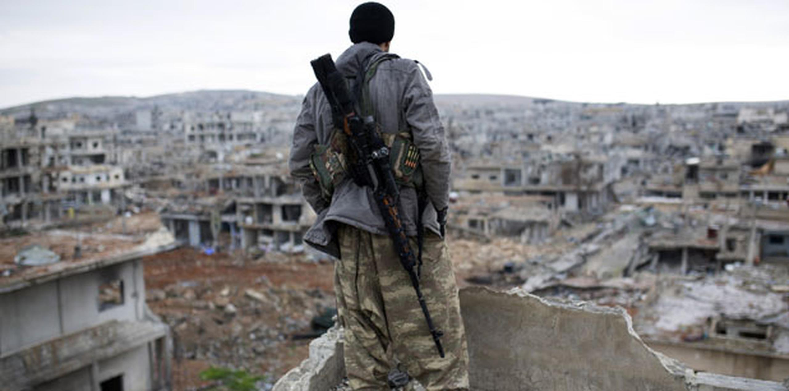 Un combatiente sirio mira las ruinas en las que ha quedado la ciudad siria kurda de Ain al Arab. (AP)
