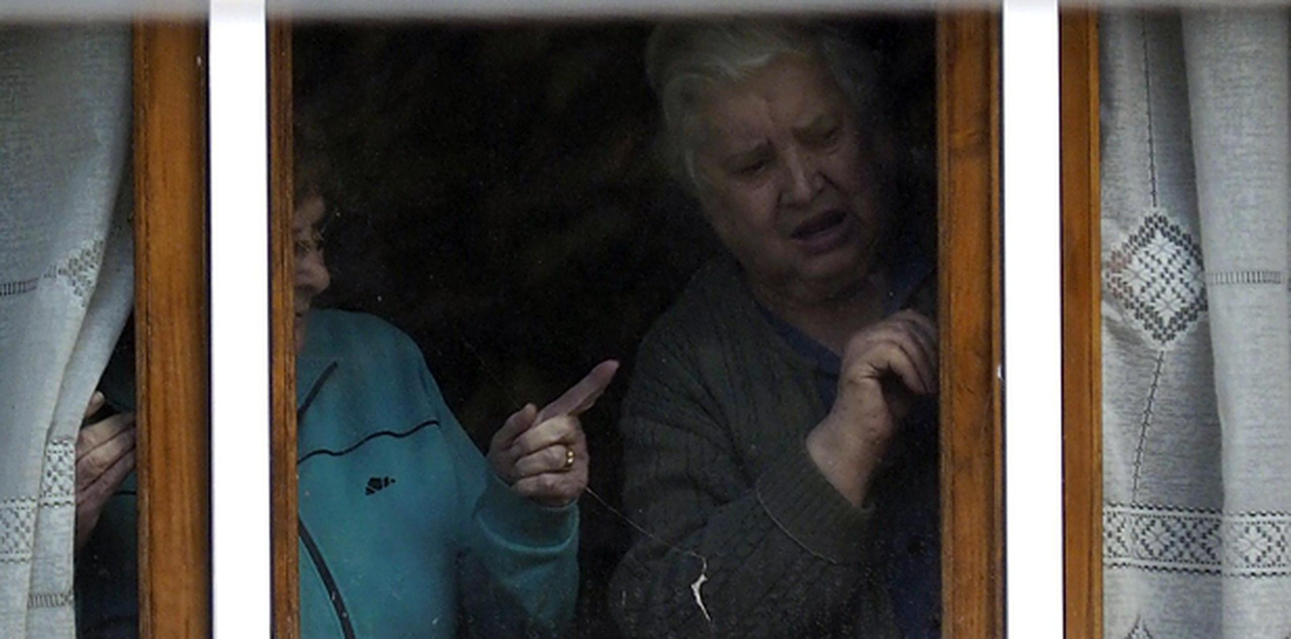 La madre (derecha) de la auxiliar de enfermería infectada de ébola, Teresa Romero Ramos, mira por la ventana de su vivienda, en Becerreá, de donde es natural la enferma que está ingresada en hospital Carlos III de Madrid. (EFE/Eliseo Trigo)