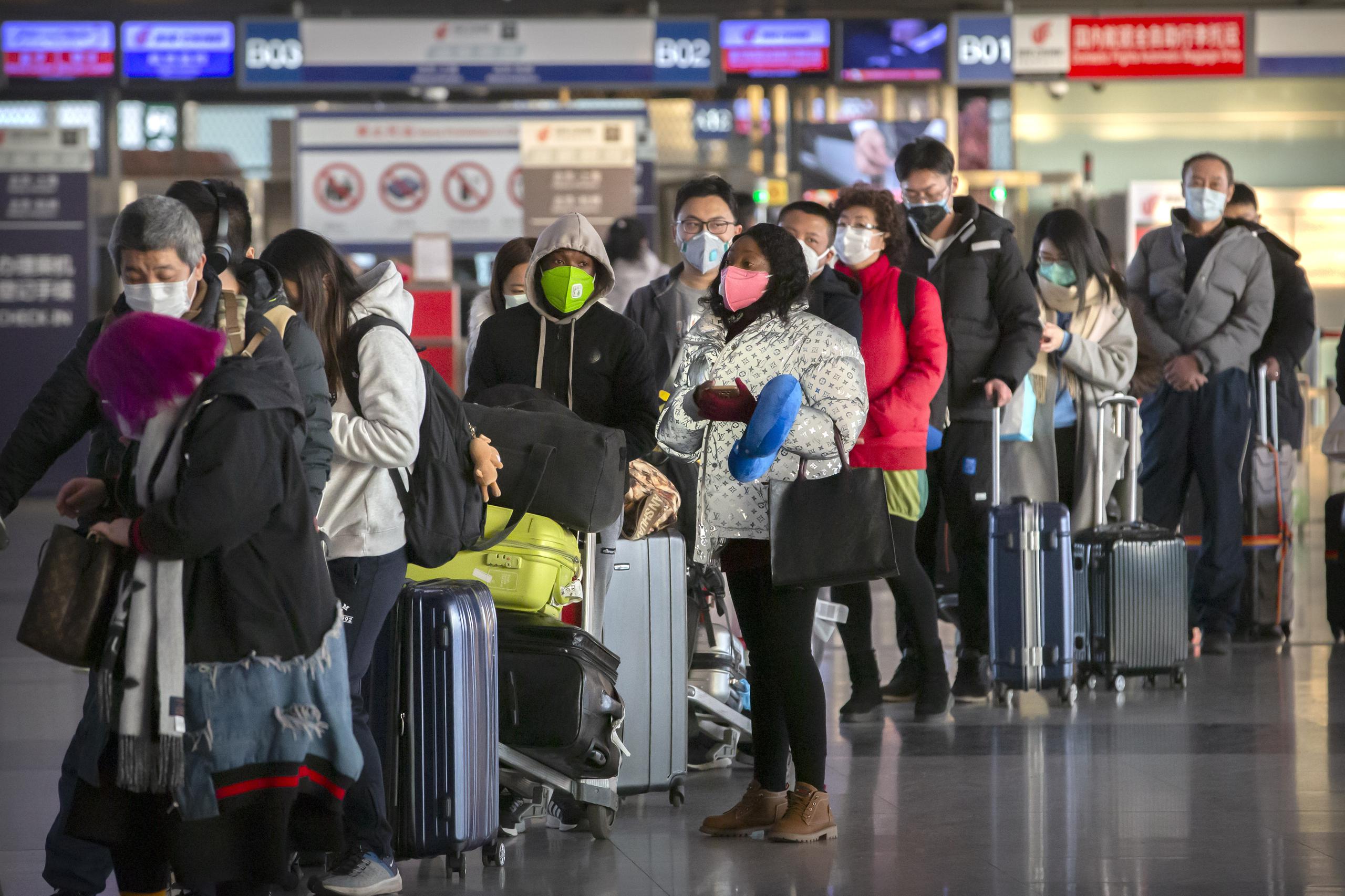 Los viajeros con máscaras faciales se alinean para registrarse para un vuelo en el Aeropuerto Internacional Capital de Beijing.