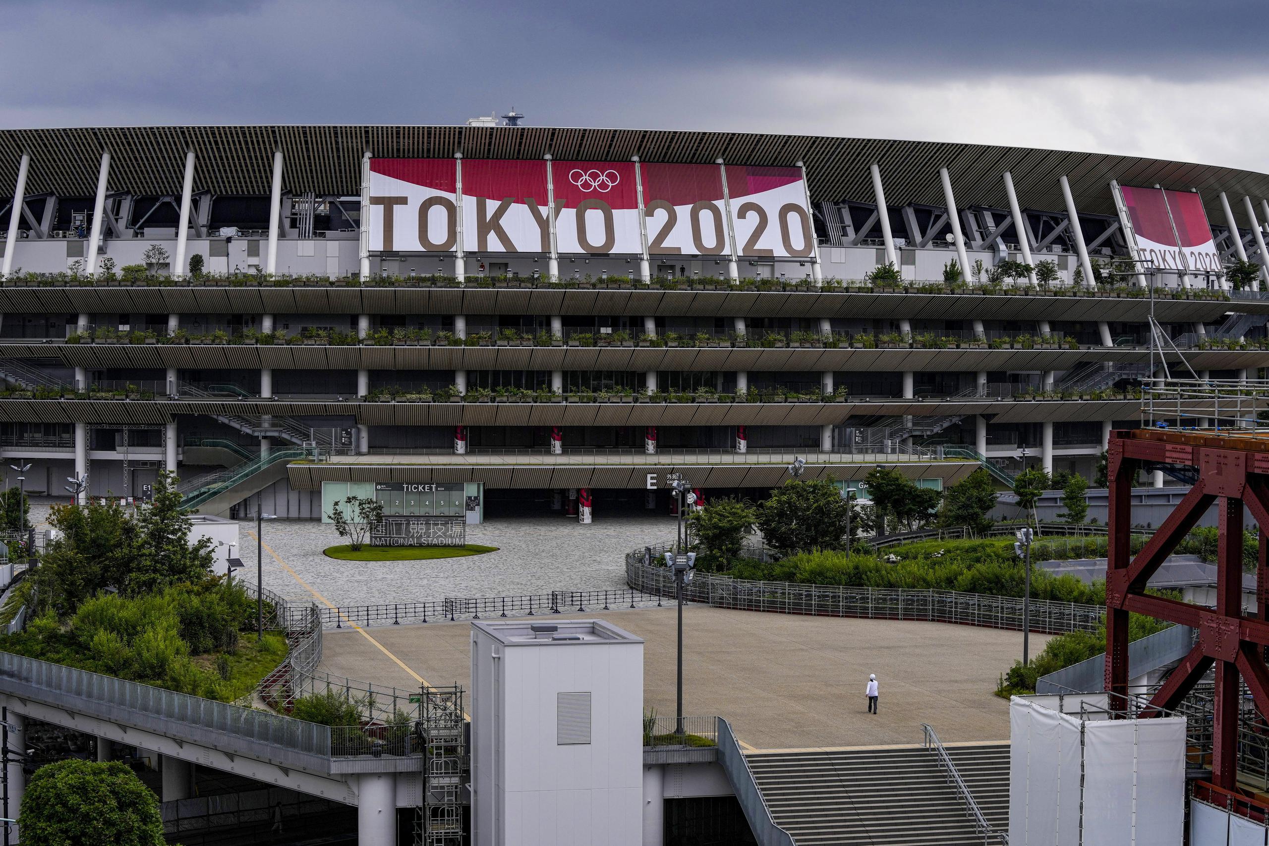 Un empleado camina frente al Estadio Nacional de Tokio, el miércoles 23 de junio de 2021, sede de las ceremonias de los Juegos Olímpicos de Tokio 2020.