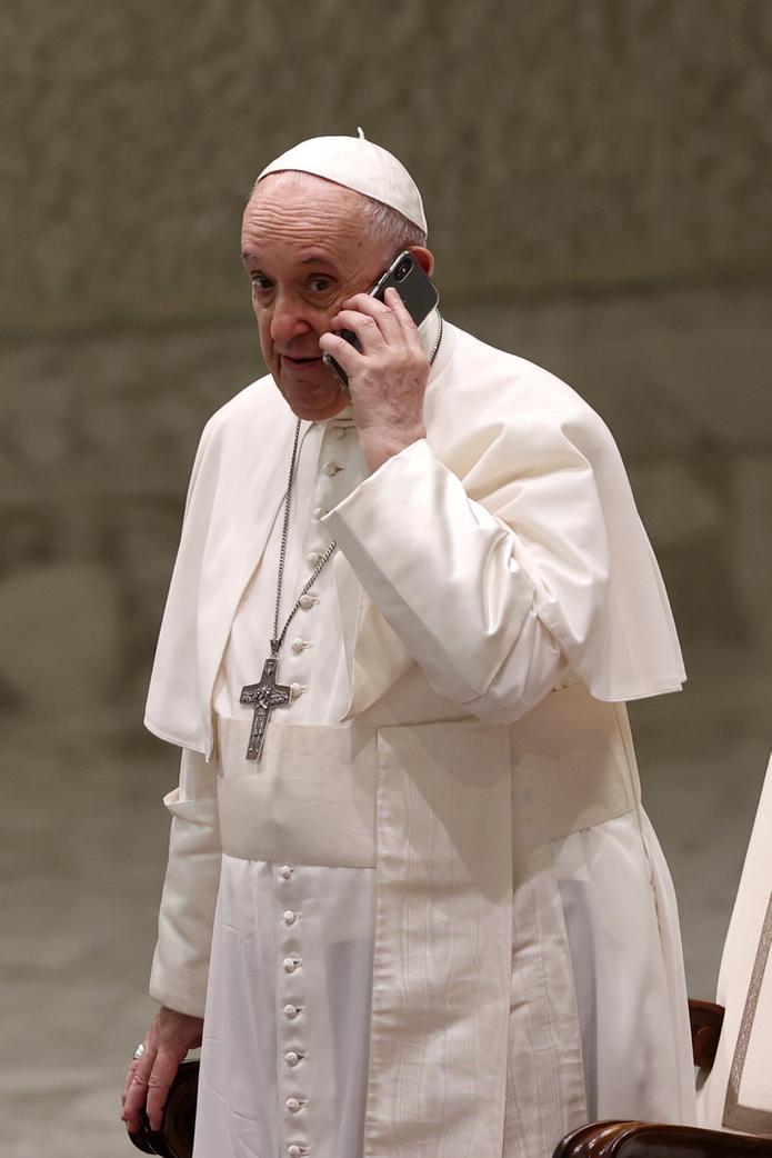 El papa Francisco habla por un teléfono celular que le entregó su asistente Piergiorgio Zanetti, al cabo de la audiencia general semanal en la Sala Paulo VI en el Vaticano, miércoles 11 de agosto de 2021. (A Foto/Riccardo De Luca)