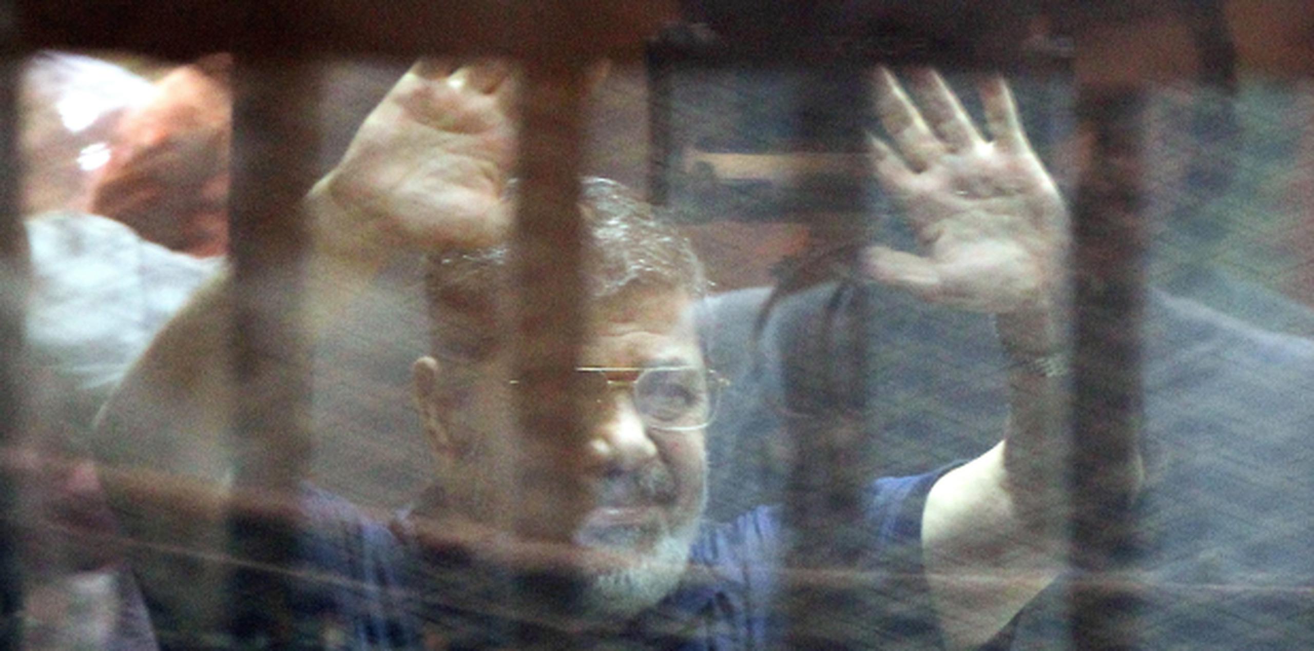 Desde una celda, Mohammed Morsi saluda a simpatizantes el día de su sentencia de muerte. (AP)