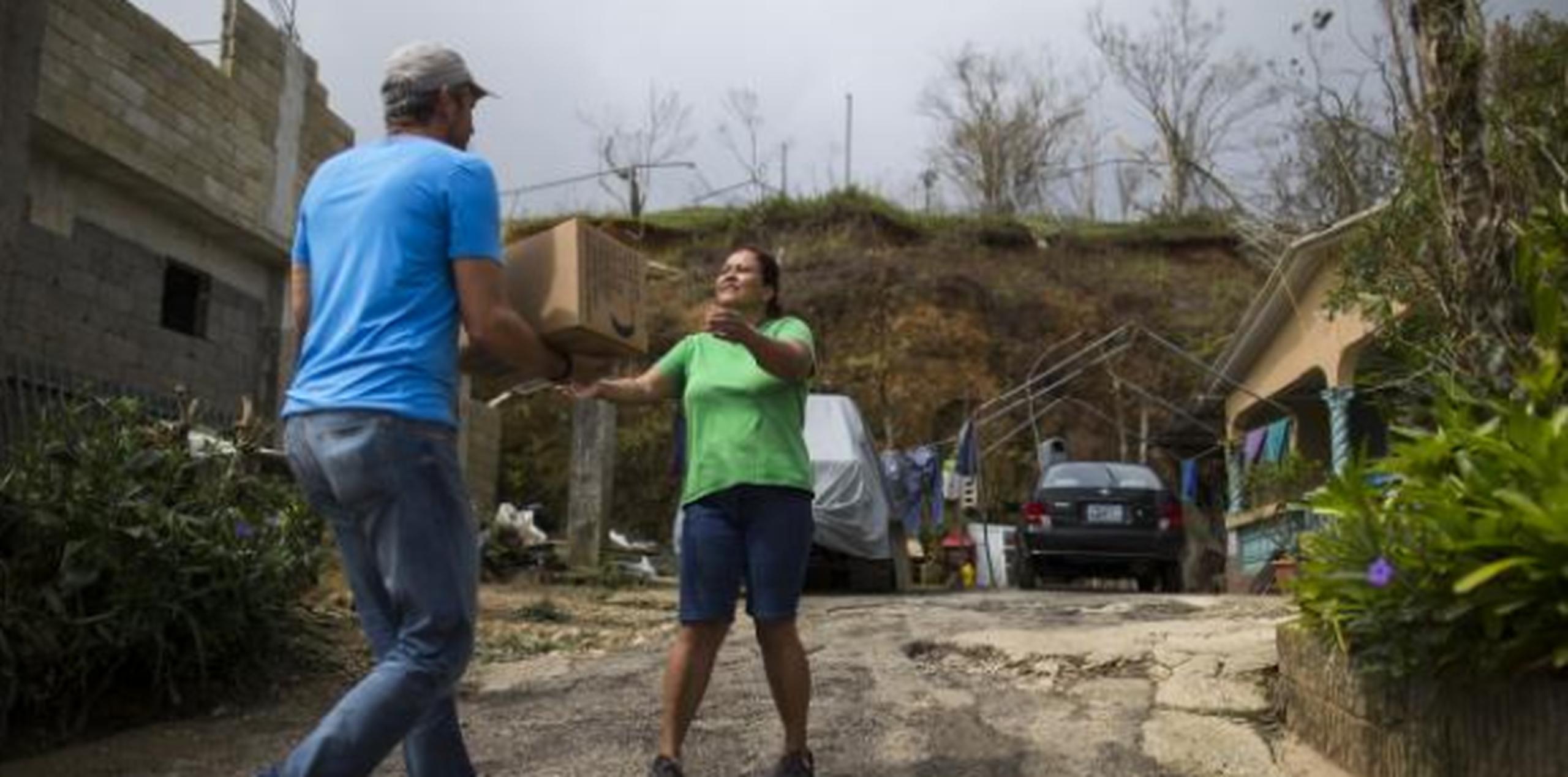 Una familia recibe una caja de agua en Coamo tras el paso del huracán maría. (Archivo)