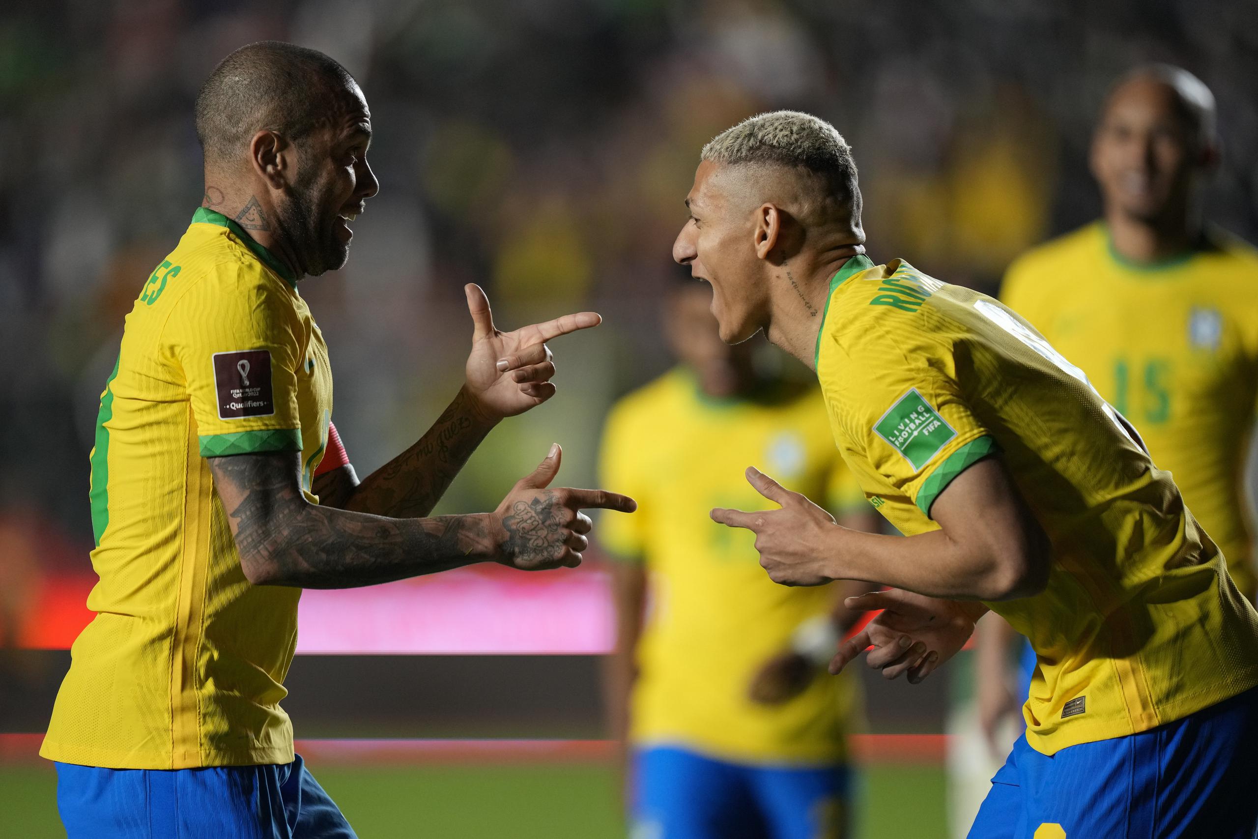 Richarlison (derecha) celebra con su compañero Dani Alves tras anotar el cuarto gol de Brasil en la victoria 4-0 ante Bolivia en las eliminatorias del Mundial, el martes 29 de marzo de 2022. (AP Foto/Juan Karita)