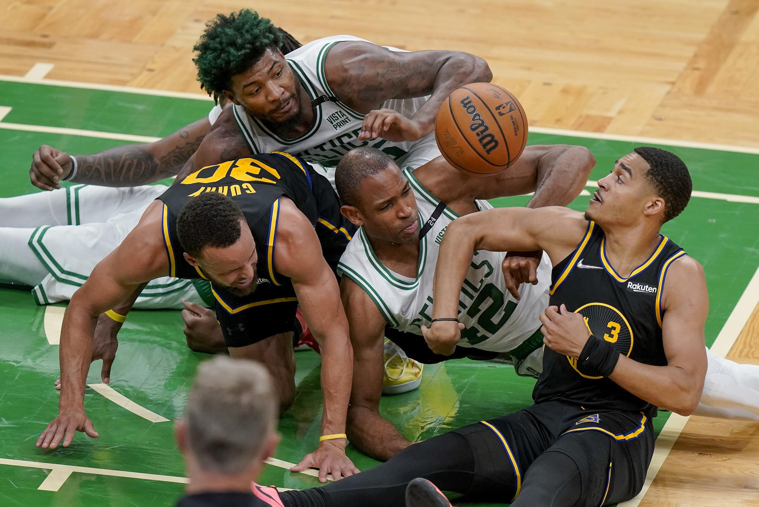 La pierna de Stephen Curry (30) quedó pillada por el cuerpo de Al Horford, de los Celtics, en la lucha por un balón perdido.