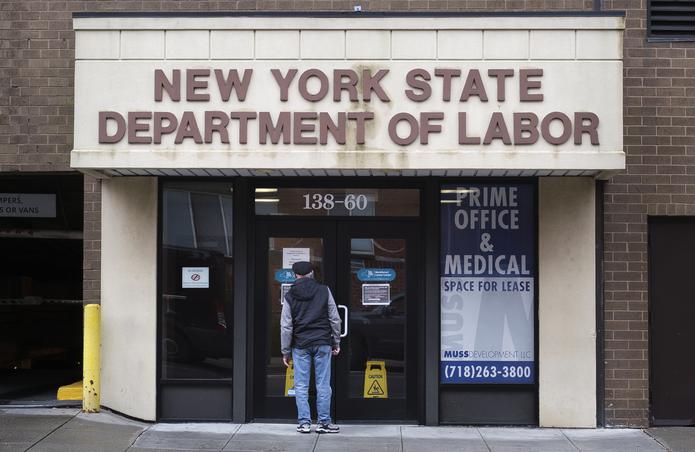 Una persona leyendo un letrero en la puerta de una oficina del Departamento de Trabajo del Estado de Nueva York, en Nueva York, EE.UU.