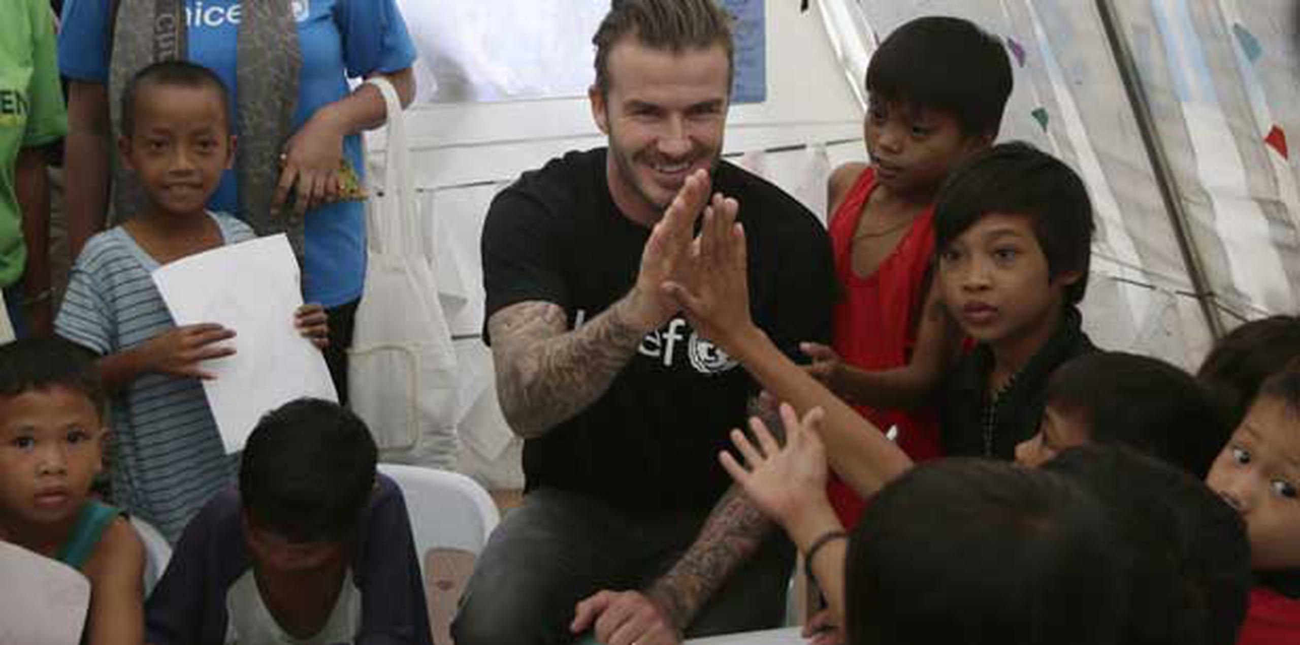 Beckham chocó sus palmas con los niños y posó para fotografías dentro de una gran carpa blanca que se utiliza como salón de clases. (Prensa Asociada)