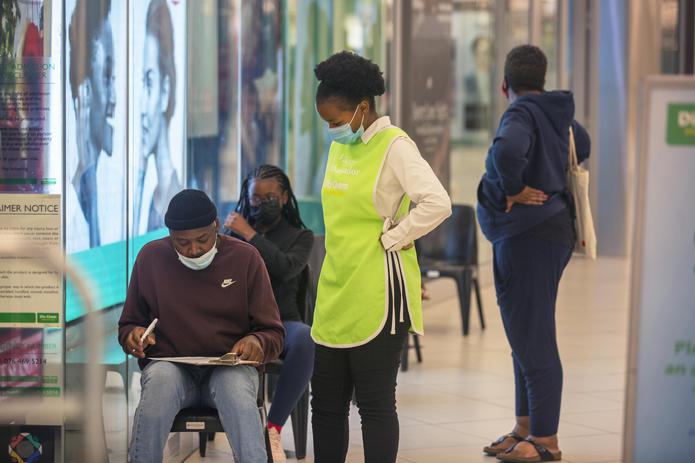 Varias personas esperan para vacunarse contra el COVID-19 en un centro comercial en Johannesburgo, Sudáfrica, donde una nueva variante del virus comienza a causar preocupación.