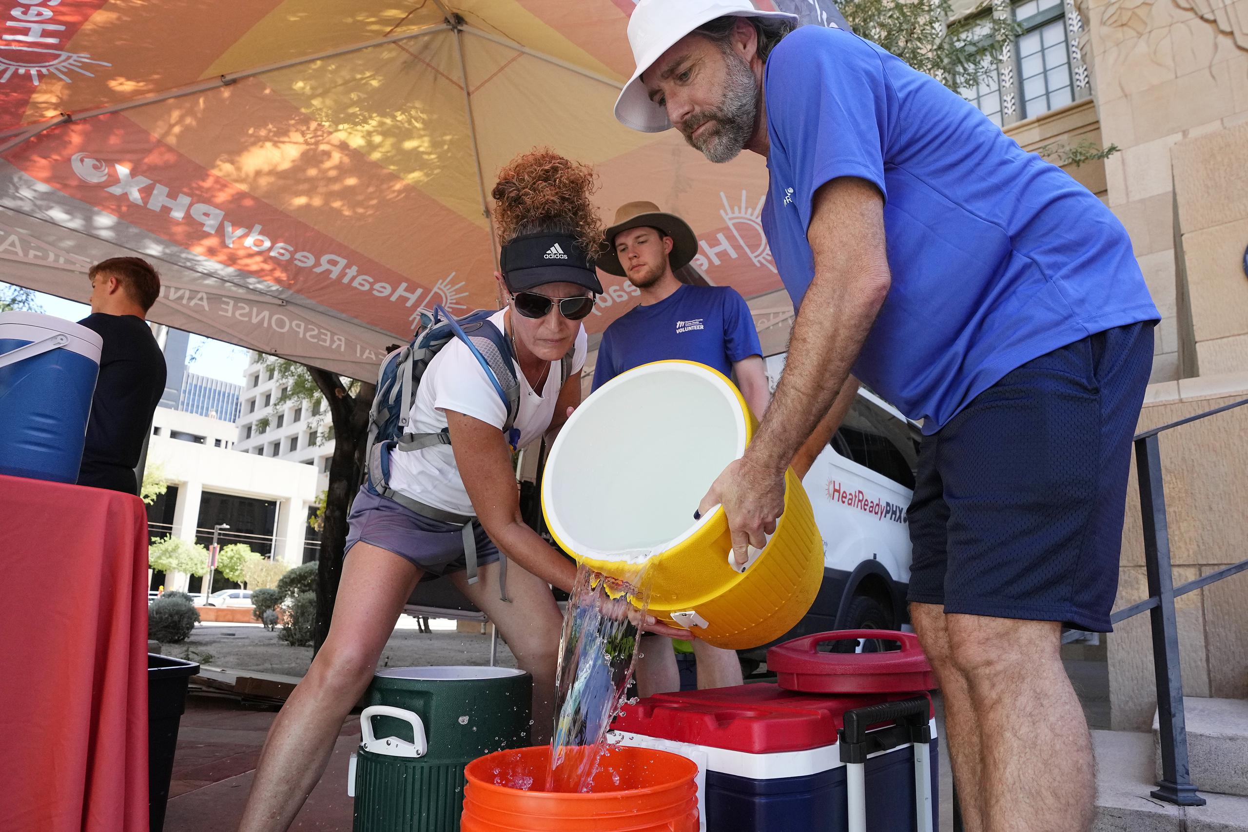 The City of Phoenix Heat Response Program team volunteers Natalie Boyd, left, and David Coughenour, right, prepare heat relief kits for the public in need as temperatures are expected to hit 119-degrees Thursday, July 20, 2023, in Phoenix. (AP Photo/Ross D. Franklin)