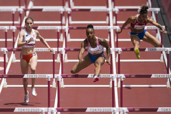 La puertorriqueña Jasmin Camacho-Quinn, al centro, rebasa una de las vallas de los 100 metros en rumbo a finalizar primera en su carrera preliminar.