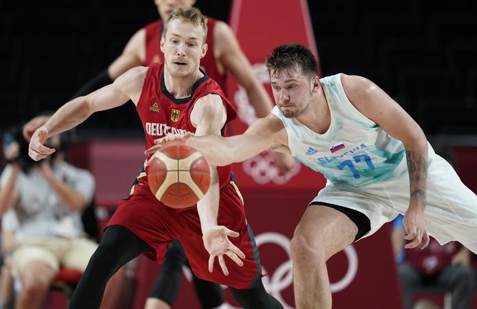 El esloveno Luka Doncic (77) y el alemán  Niels Giffey, se disputan una bola suelta durante el choque entre ambas selecciones en el baloncesto de los Juegos Olímpicos Tokio 2020.
