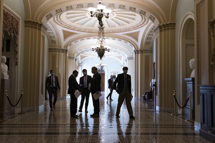 Miembros del Senado esperaban en el pasillo a las afueras del hemiciclo durante uno de los recesos que han demorado la sesión.