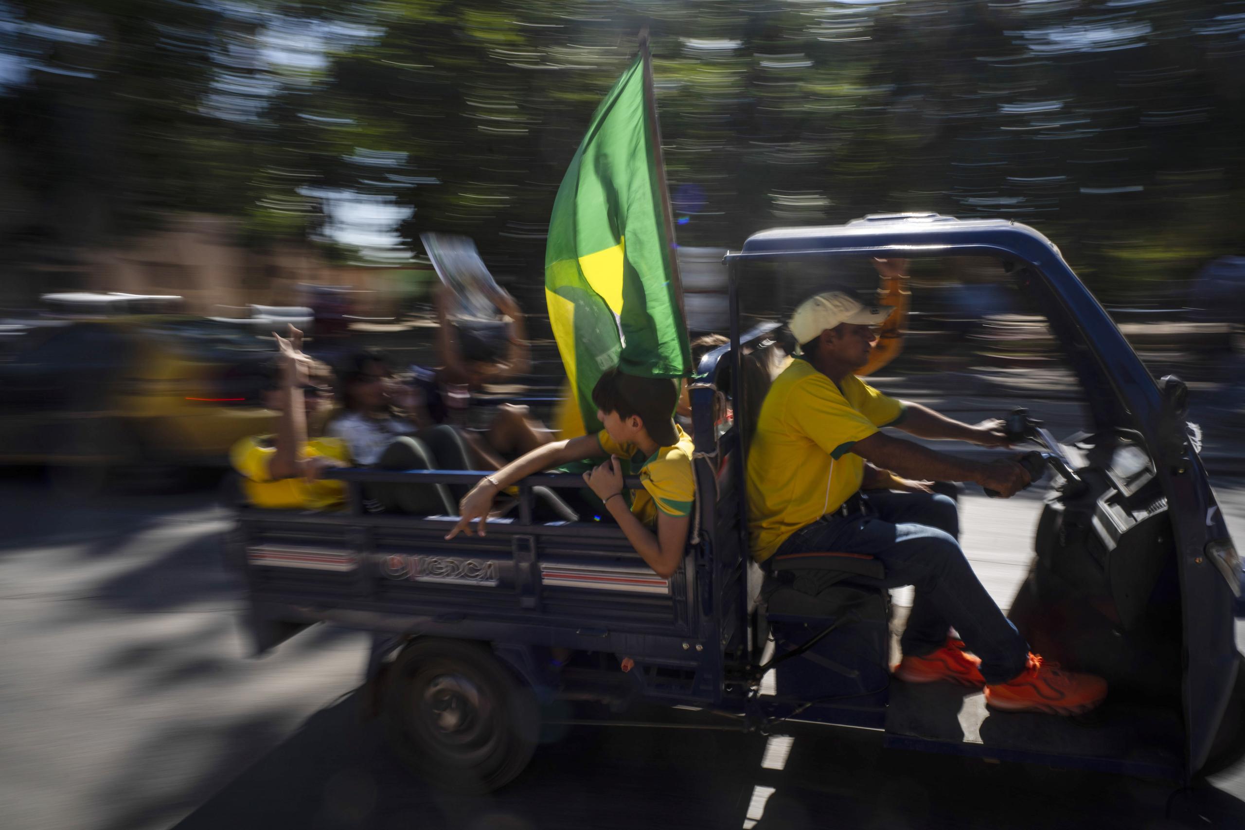 Seguidores cubanos de la selección brasileña de fútbol llegan en un taxi para mirar el partido entre la selección de Brasil y Suiza mediante una pantalla gigante en Bauta, Cuba, el lunes 28 de noviembre de 2022 (AP Foto/Ramón Espinosa)