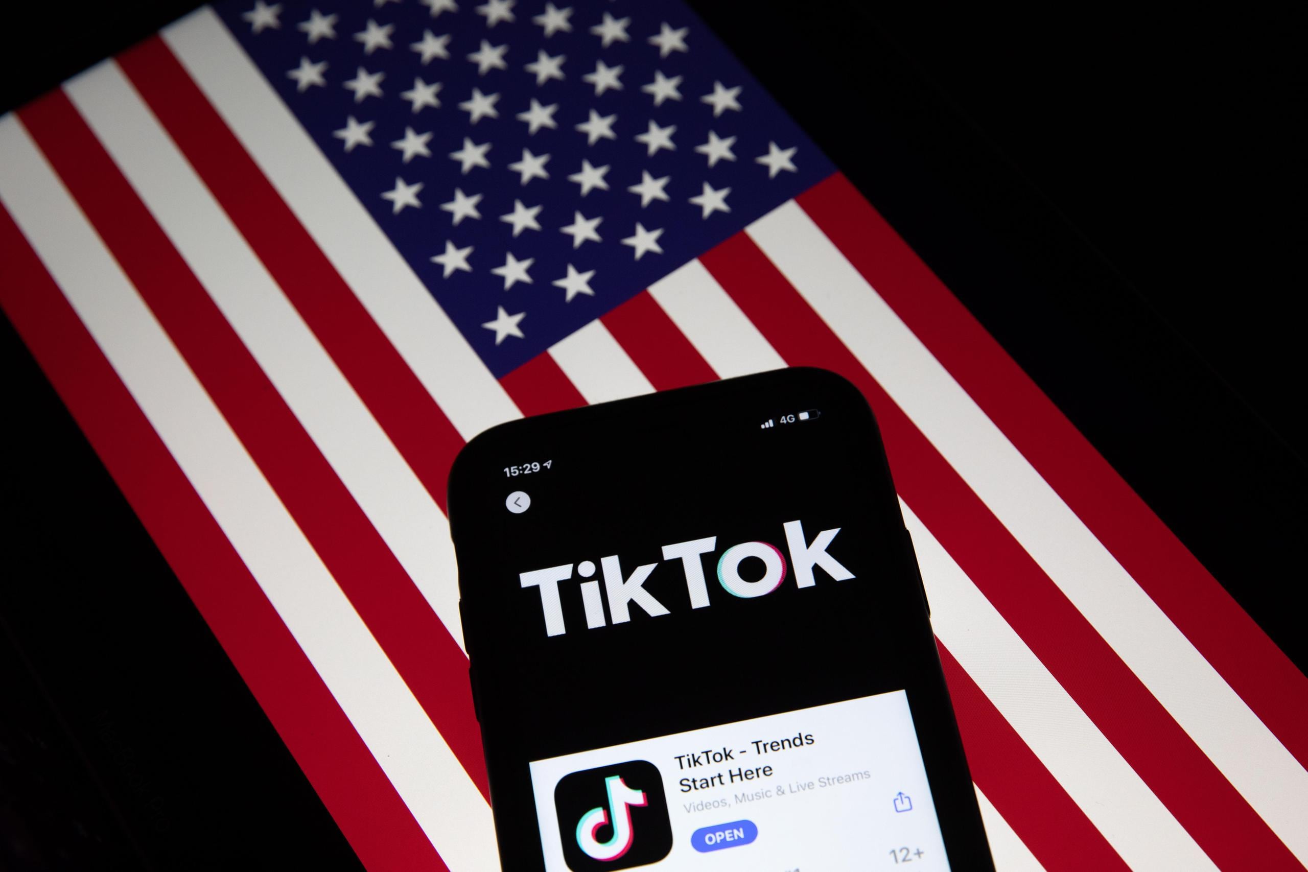 El app TikTok y, al fondo, la bandera de Estados Unidos.
