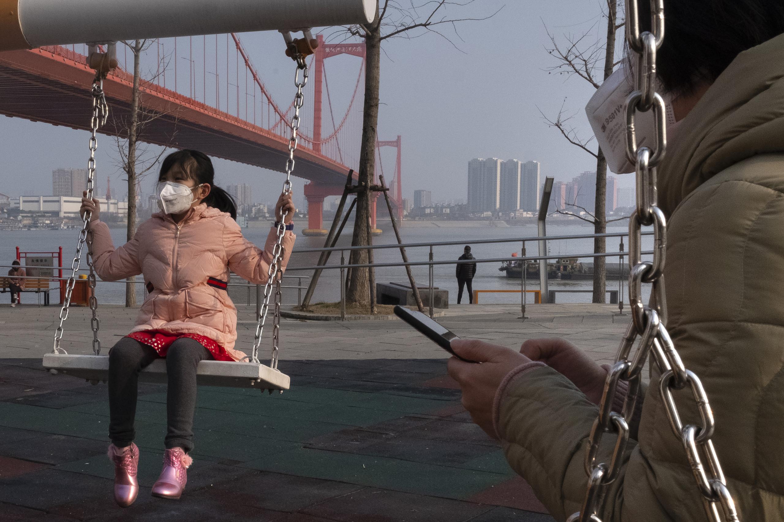 Una niña usa una mascarilla mientras se columpia en la ciudad de Wuhan, China. (AP)
