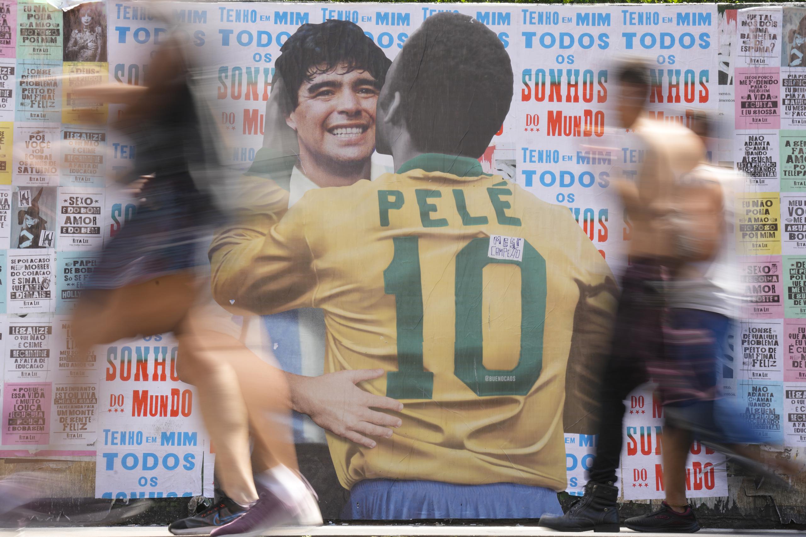 La gente pasa frente a un cartel que muestra al brasileño Pelé y al argentino Diego Maradona en Sao Paulo, el sábado 24 de diciembre de 2022.