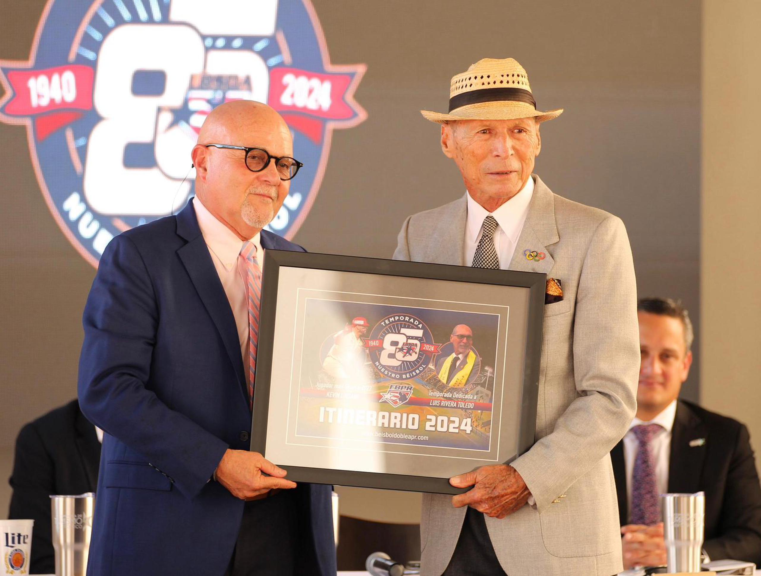 José Quiles, presidente de la Federación de Béisbol, le presentó a Luis Rivera Toledo una copia ampliada del calendario de la temporada 2024.