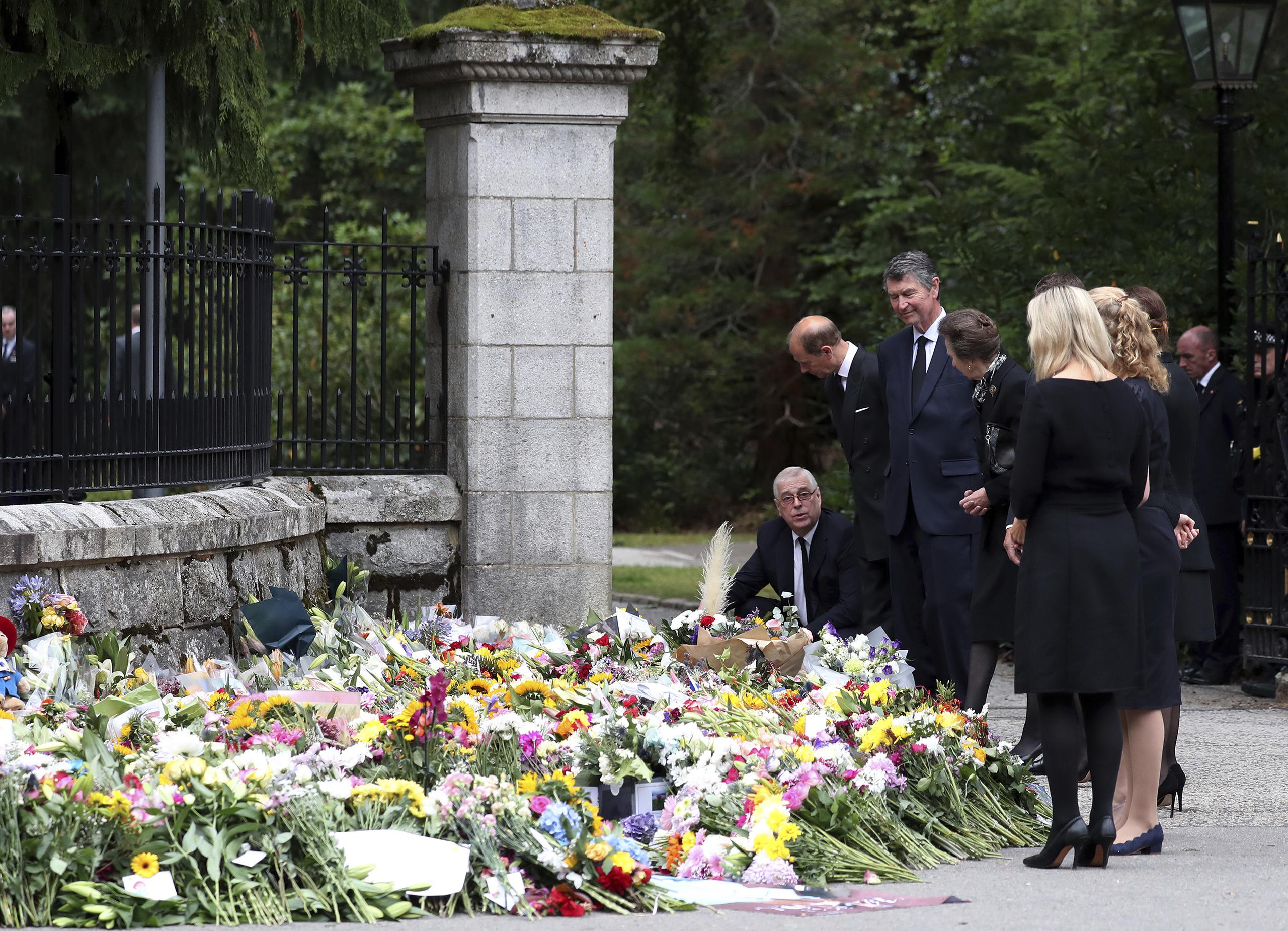 Miembros de la familia real miran los tributos florales dejados a las afueras del castillo de Balmoral, donde hoy descansan los restos de la reina.