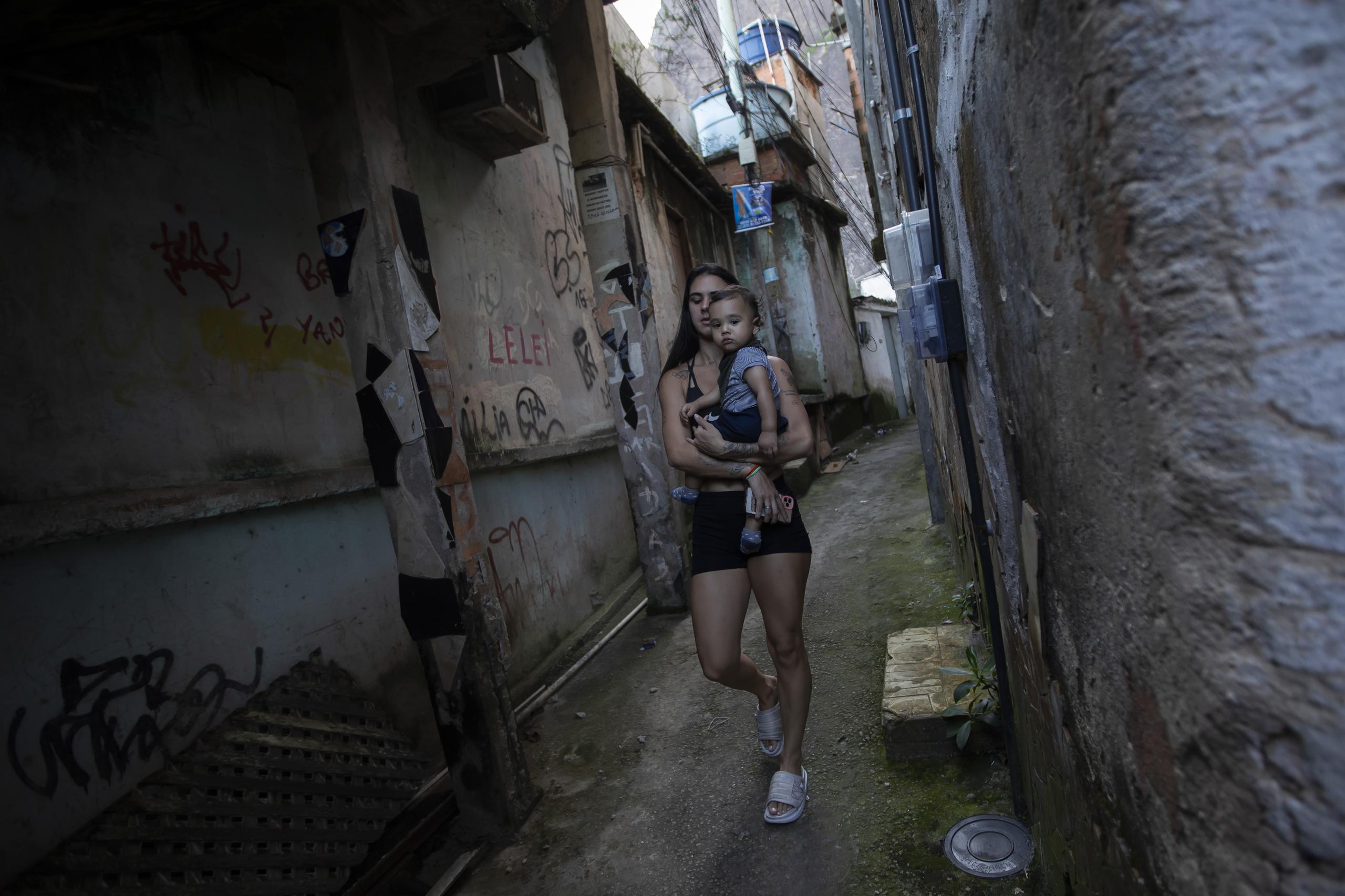 La clavadista brasileña Giovanna Pedroso camina con su hijo Nicolás Pedros en la favela Chacara do Ceu de Río de Janeiro.