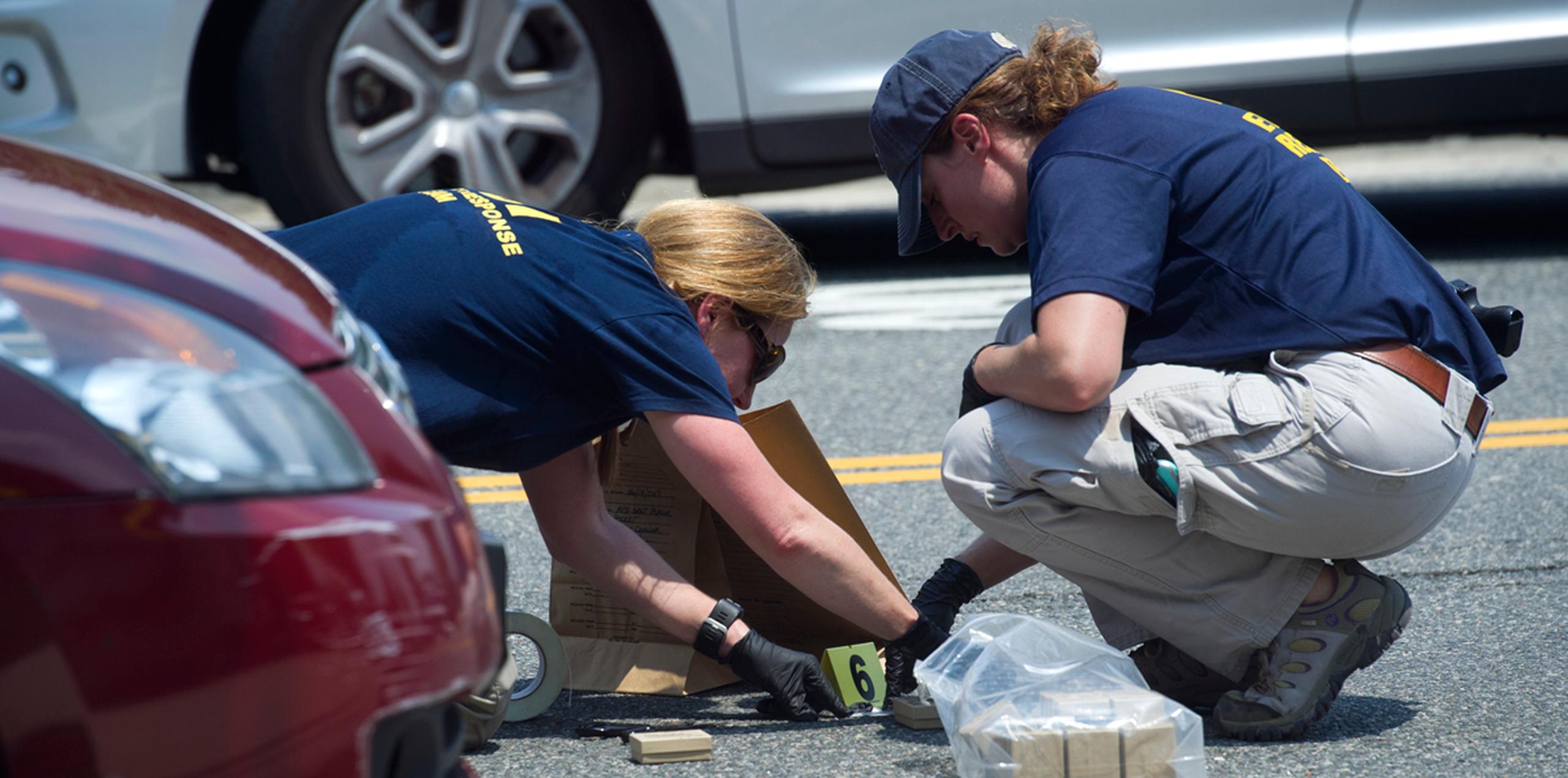 Miembros de un equipo del FBI señalan la presencia de pruebas en el lugar de un tiroteo en Alexandria, Virginia. (AP)