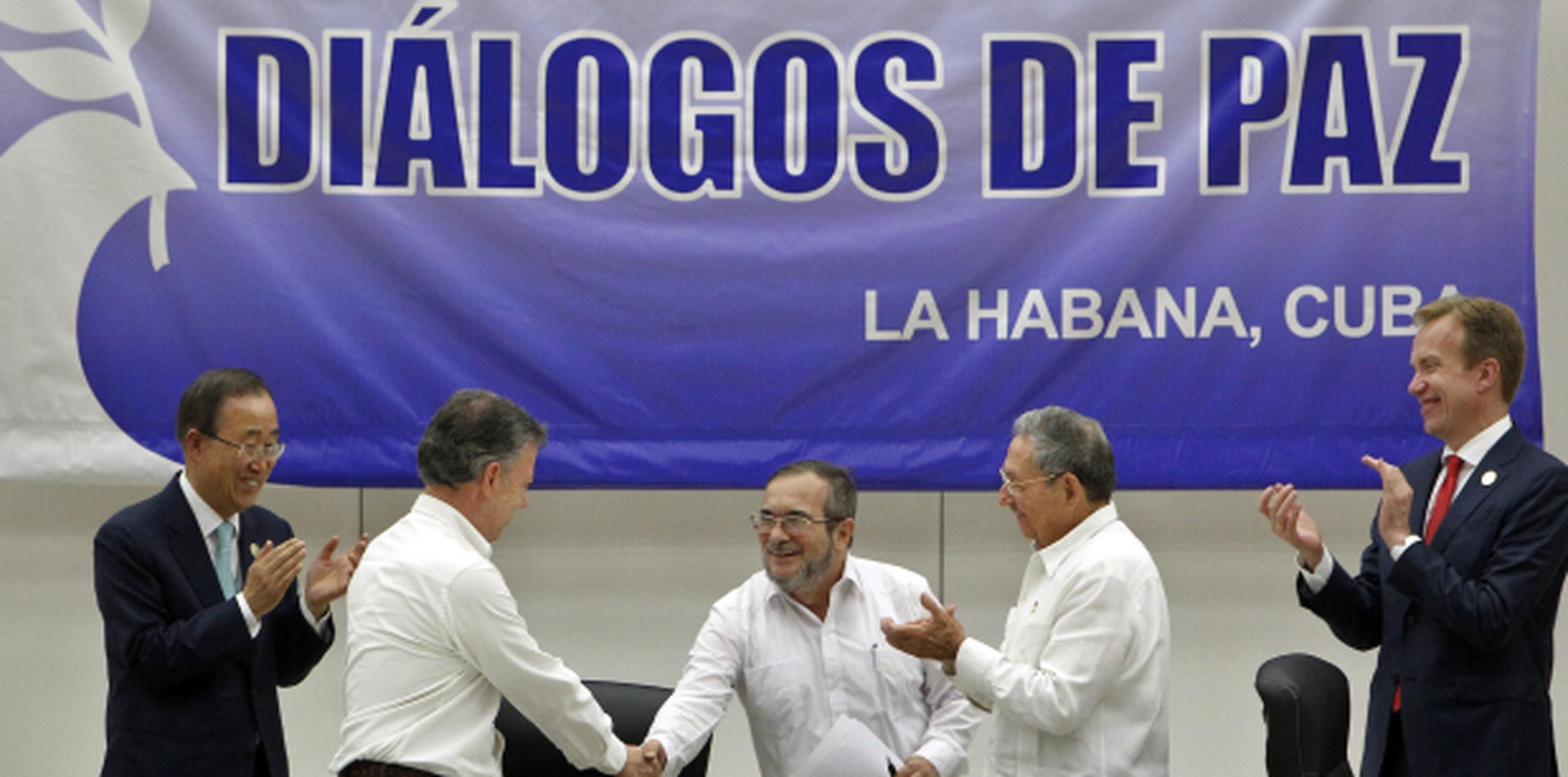 Al centro estrechan las manos el líder de las FARC, Rodrigo Londoño Echeverri y el presidente de Colombia, Juan Manuel Santos (de espalda). Observan Raúl Castro, de Cuba, el ministro noruego Borge Brende y al secretario general de la ONU, Ban Ki-moon. (EFE)