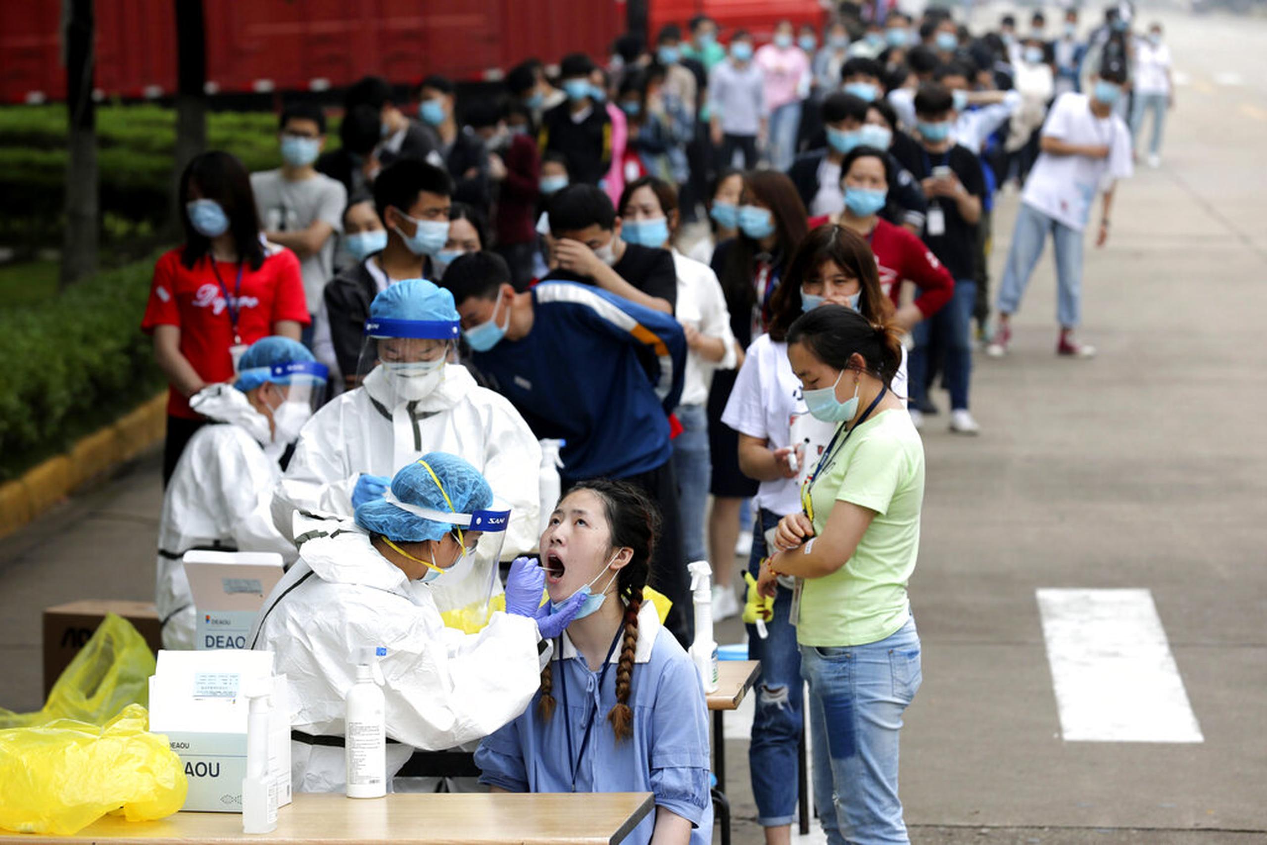En esta imagen de archivo, tomada el 15 de mayo de 2020, trabajadores hacen fila para someterse a una prueba de detección del coronavirus en una fábrica en Wuhan, en la provincia de Hubei, en el centro de China.
