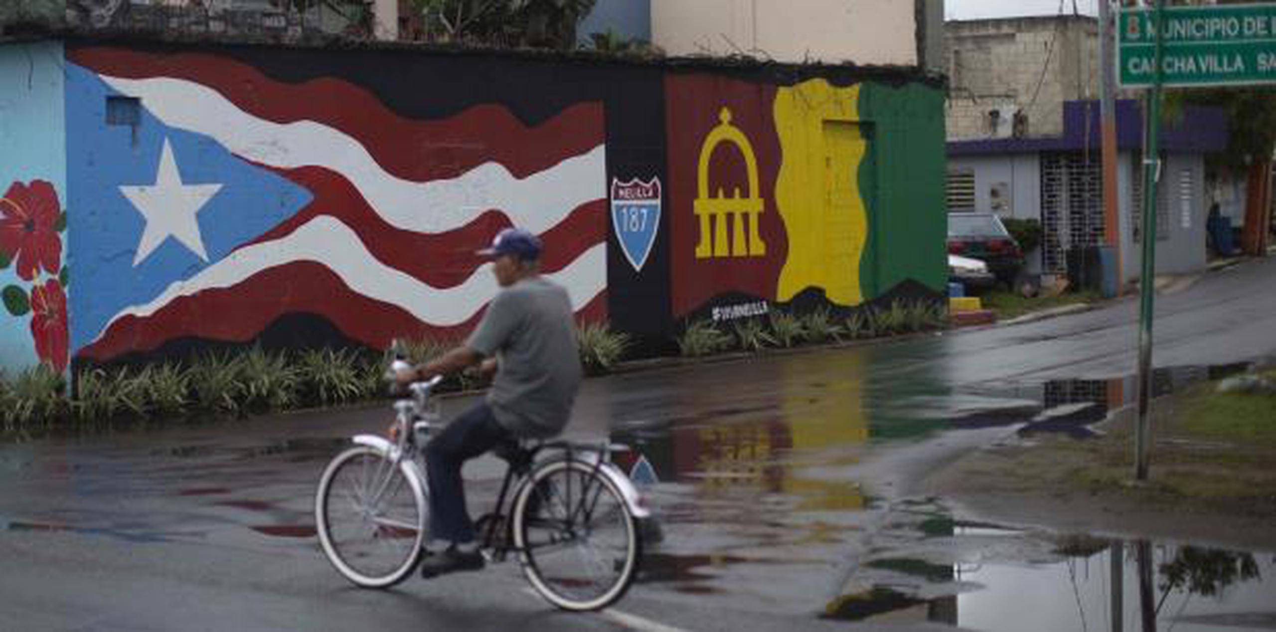 Un hombre corre su bicicleta sobre pavimento mojado. (Archivo)