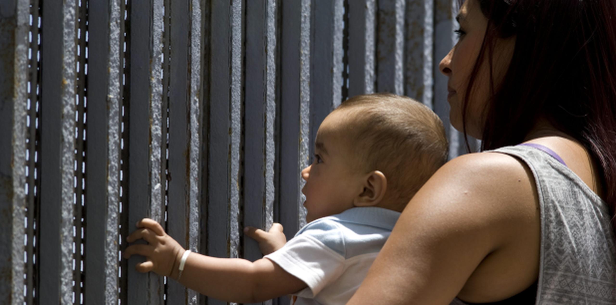 Jazmín Parra sostiene a su bebé de nueve meses para que vea a su papá, Christian Esquer, quien se encuentra al otro lado de la verja, y de la frontera entre Estados Unidos y México. (EFE)