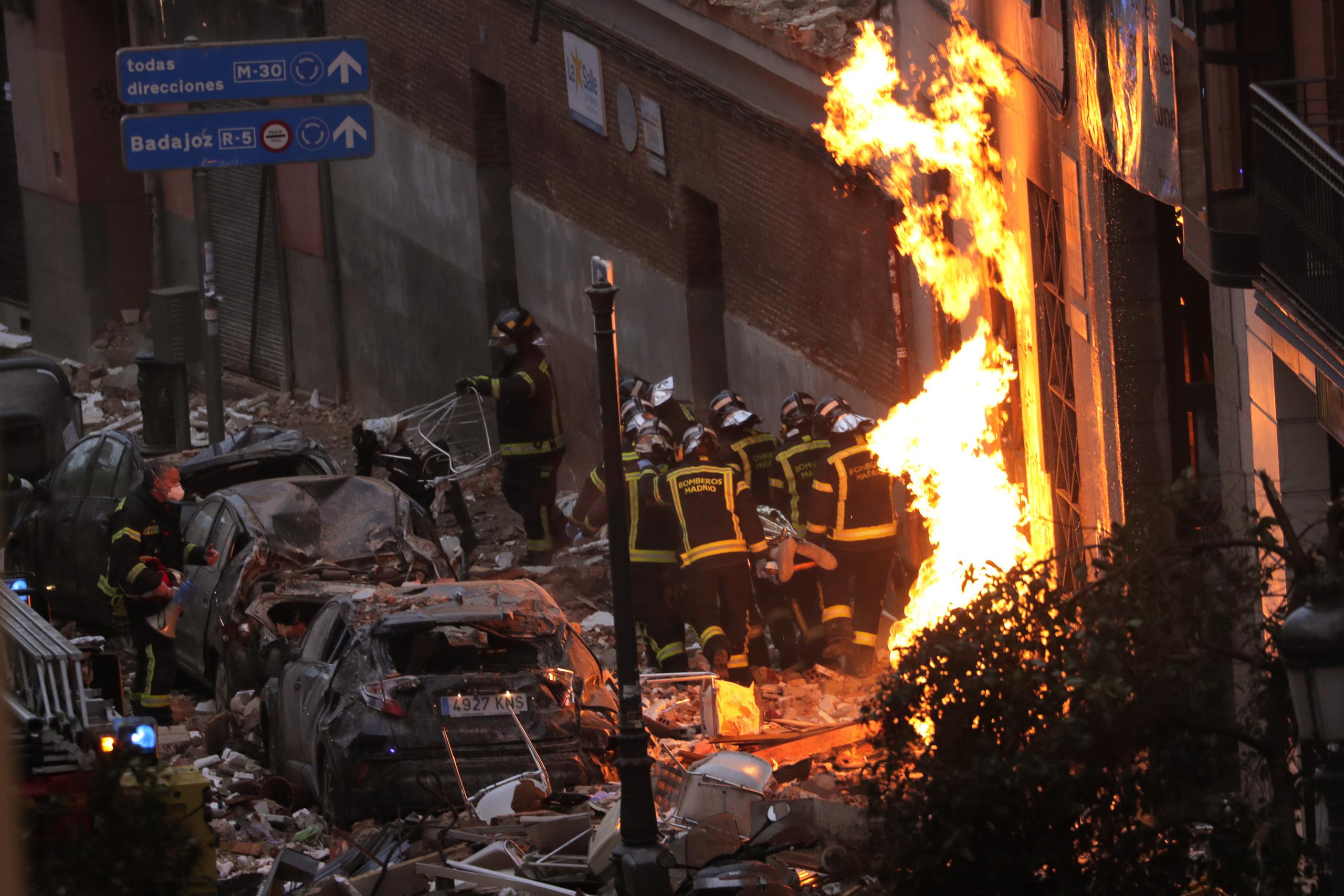 Los bomberos llevan un cadáver junto a un edificio dañado en la calle Toledo tras una explosión en el centro de Madrid, España.