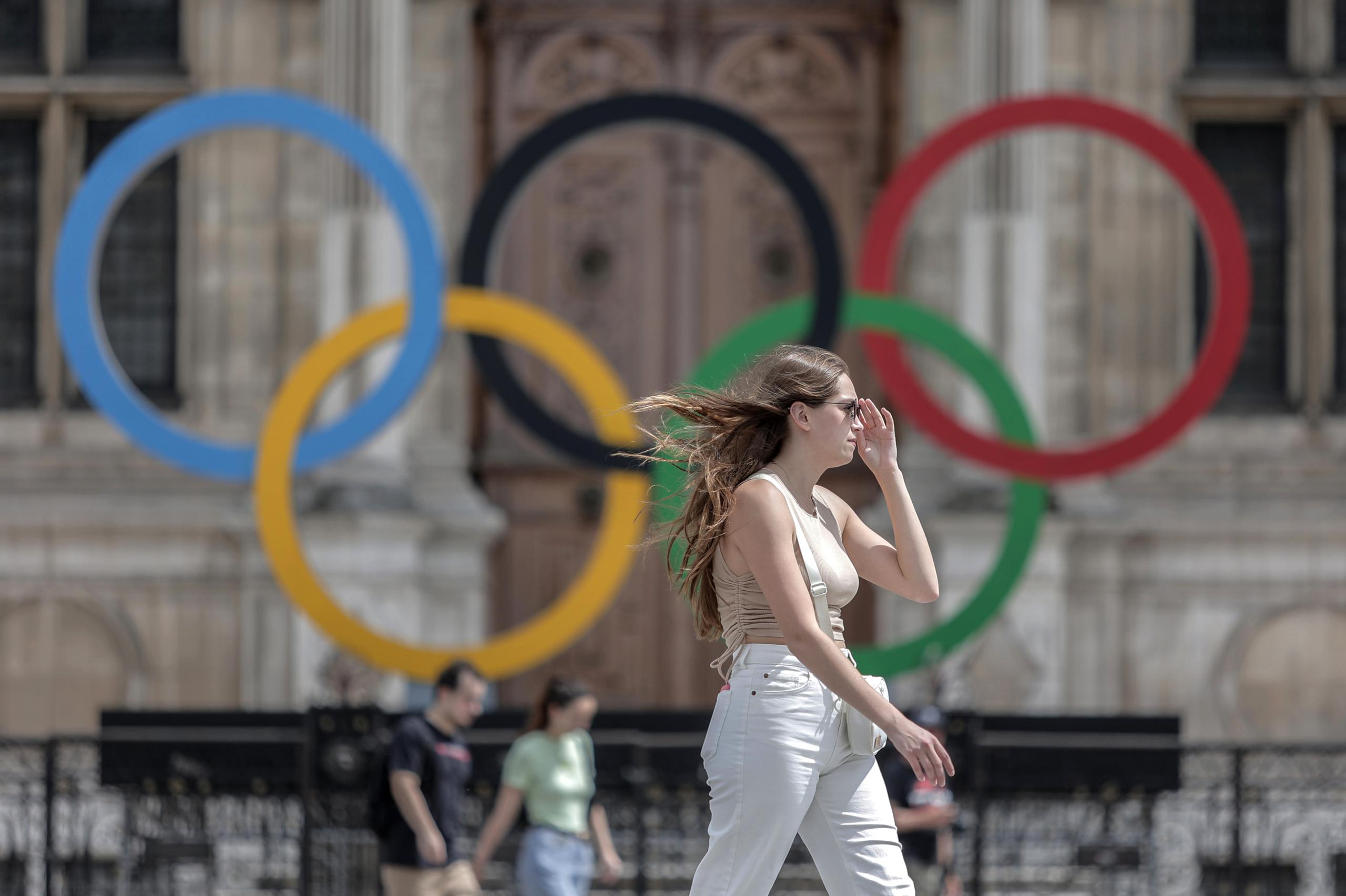 En esta foto del 25 de julio del 2022, una mujer pasa junto a los aros olímpicos afuera del ayuntamiento de París.