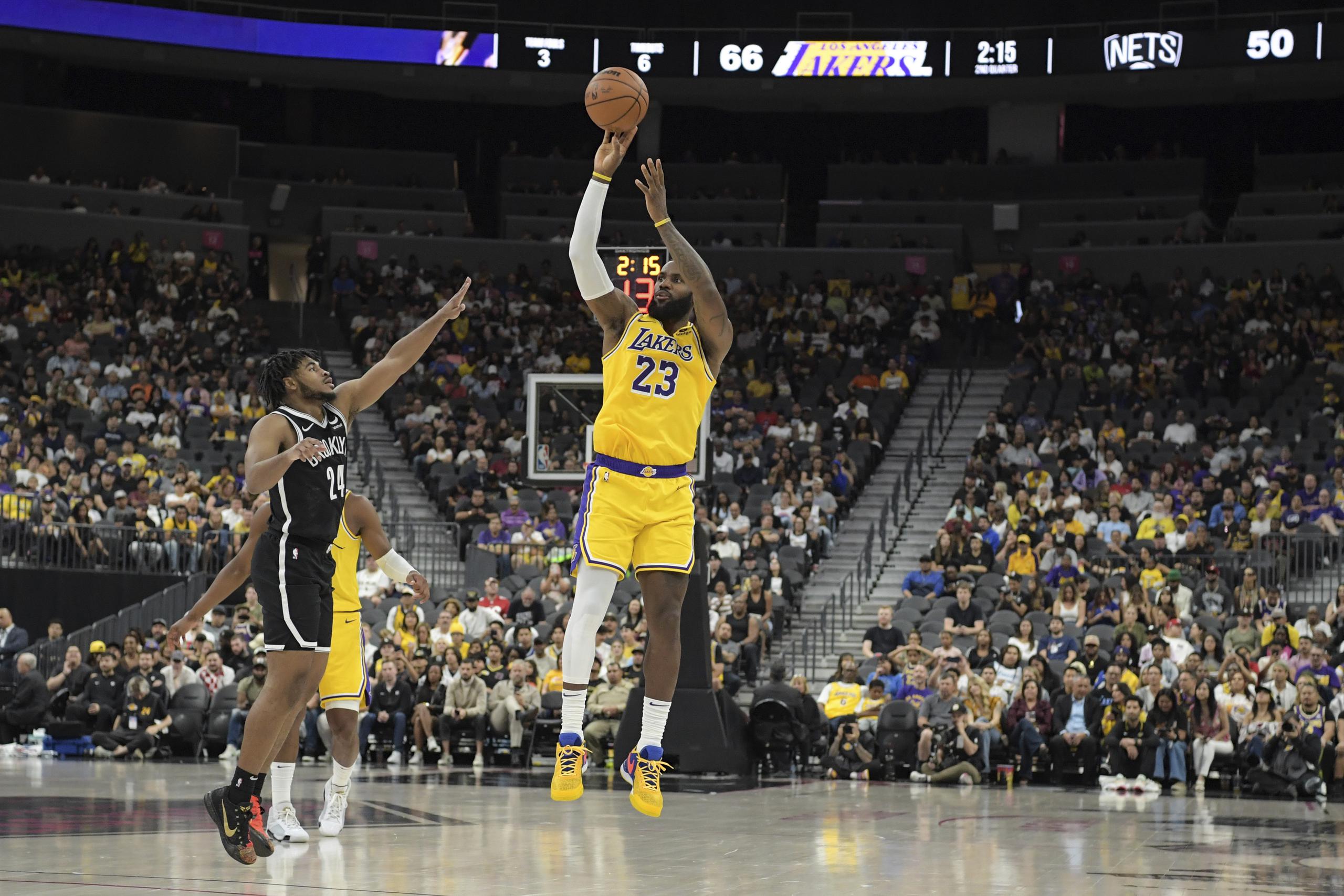 El alero de los Lakers de Los Ángeles, LeBron James, lanza un triple sobre el base de los Nets de Brooklyn Cam Thomas durante el encuentro de pretemporada.