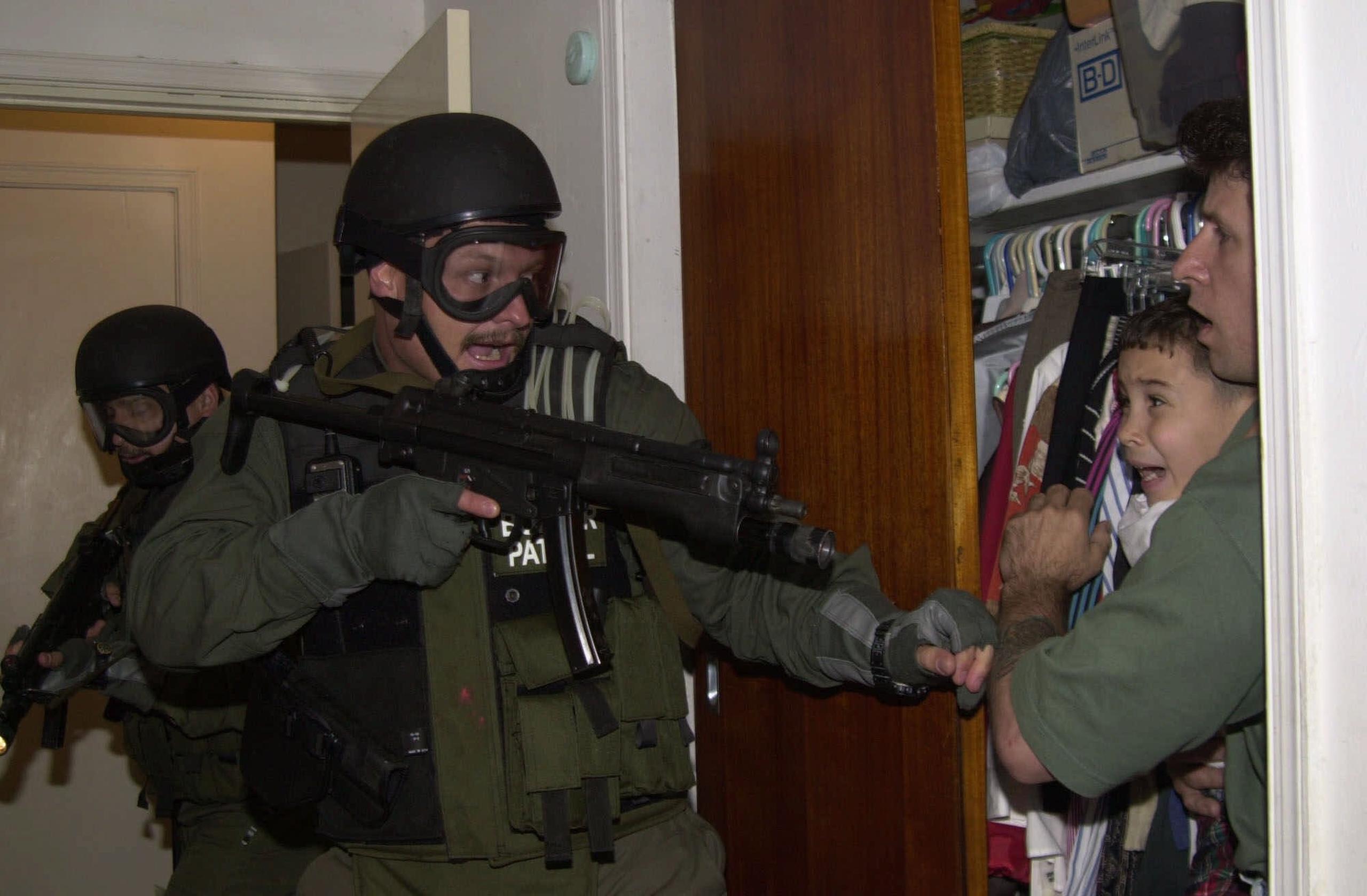 El pescador Donato Dalrymple sostiene a Elián González, de 6 años, dentro de la habitación de Lázaro González durante la madrugada del sábado 22 de abril de 2000, cuando agentes de la Patrulla Fronteriza irrumpieron en la casa de Miami para tomar la custodia de el niño.