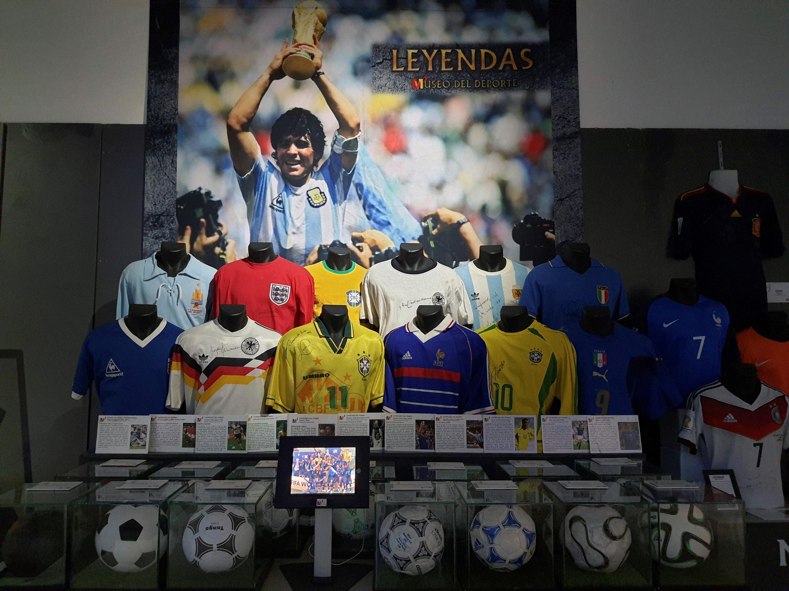 Una foto del jugador de Diego Armando Maradona junto a las camisetas de los mejores jugadores del mundo está expuesta dentro de la muestra "Leyendas del Deporte" en un centro comercial madrileño.
