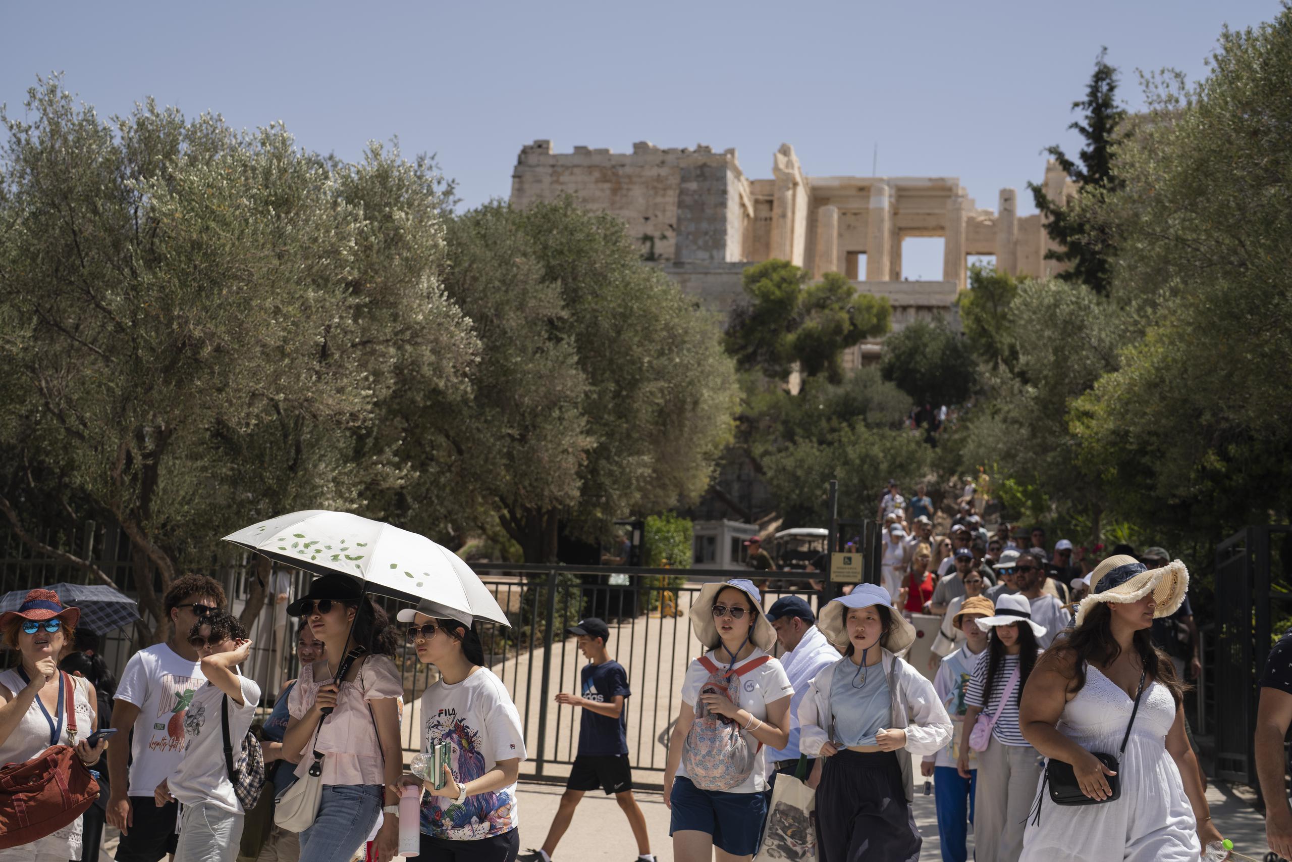 Turistas salen de la Acrópolis de Atenas luego de que el Ministerio de Cultura de Grecia cerró el monumento por el calor, el viernes 14 de julio de 2023. (AP Foto/Petros Giannakouris)